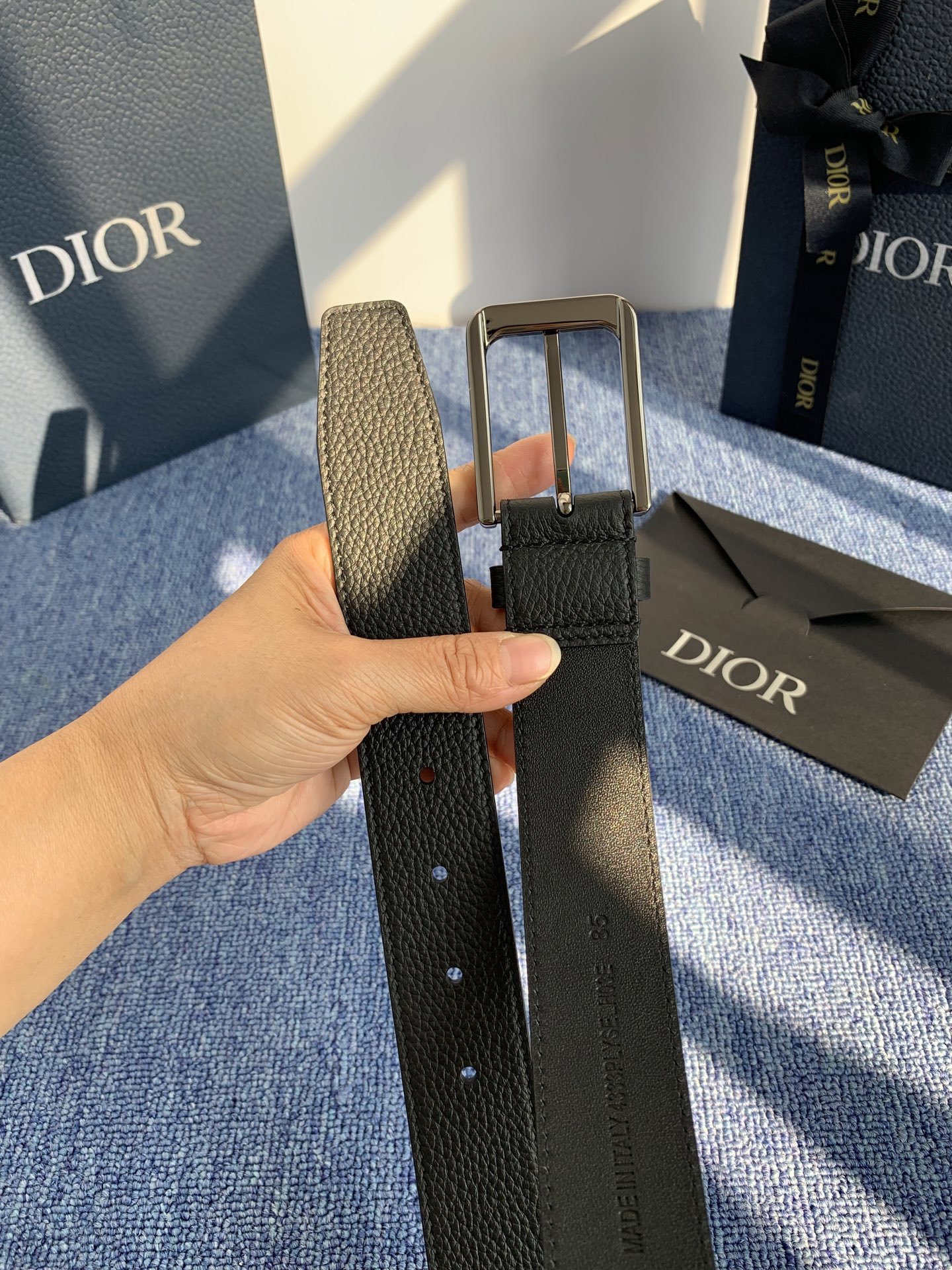 采用黑色粒面牛皮革精心制作，饰以镌刻有 Dior 的针扣和黑色金属覆层铜合金 CD Icon 标志腰带环