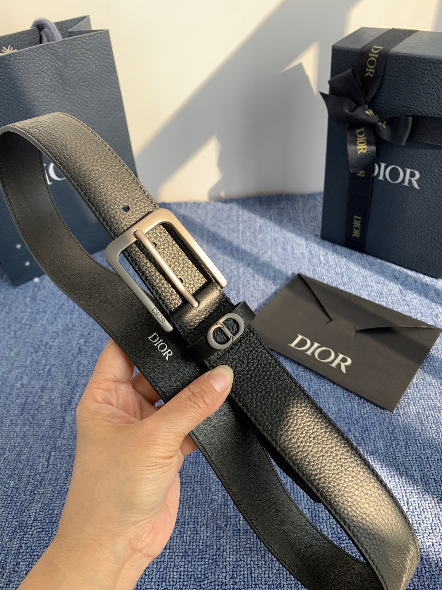 采用黑色粒面牛皮革精心制作，饰以镌刻有 Dior 的针扣和黑色金属覆层铜合金 CD Icon 标志腰带环