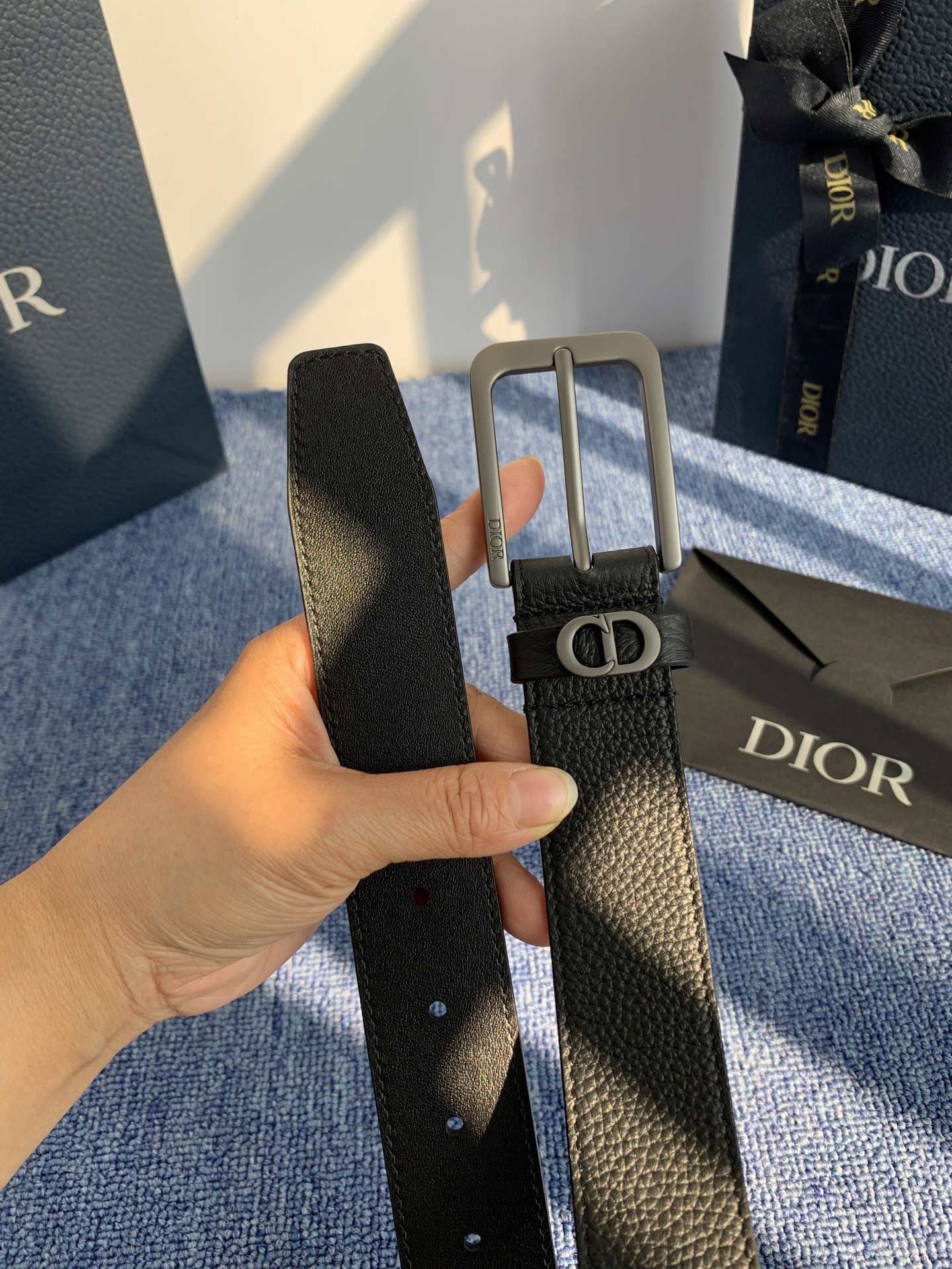 采用黑色粒面牛皮革精心制作，饰以镌刻有 Dior 的针扣和黑色金属覆层铜合金 CD Icon 标志腰带环
