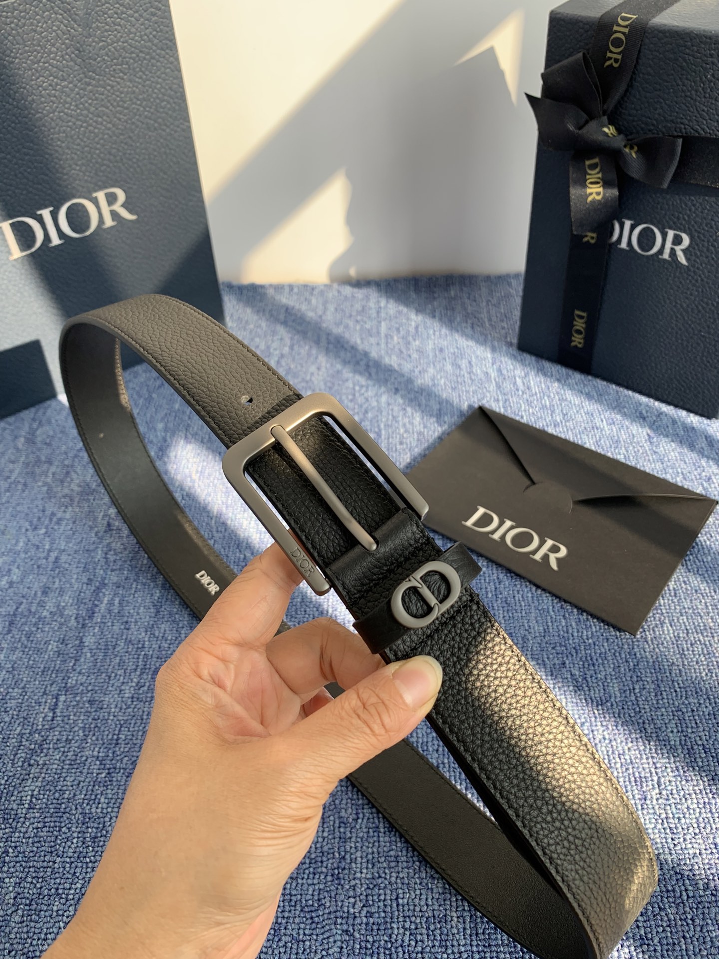 采用黑色粒面牛皮革精心制作，饰以镌刻有 Dior 的针扣和黑色金属覆层铜合金 CD Icon 标志腰带环