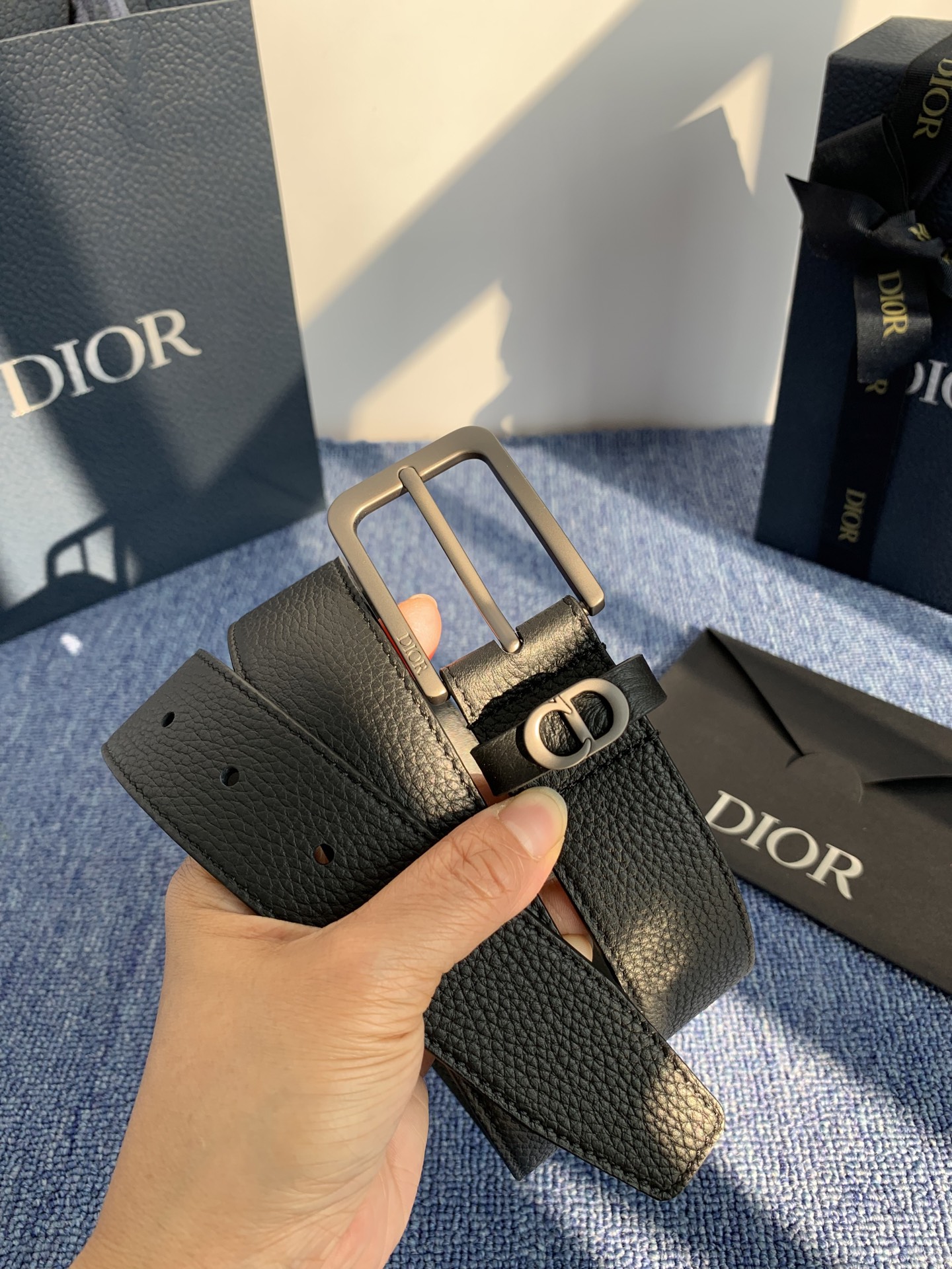 采用黑色粒面牛皮革精心制作，饰以镌刻有 Dior 的针扣和黑色金属覆层铜合金 CD Icon 标志腰带环