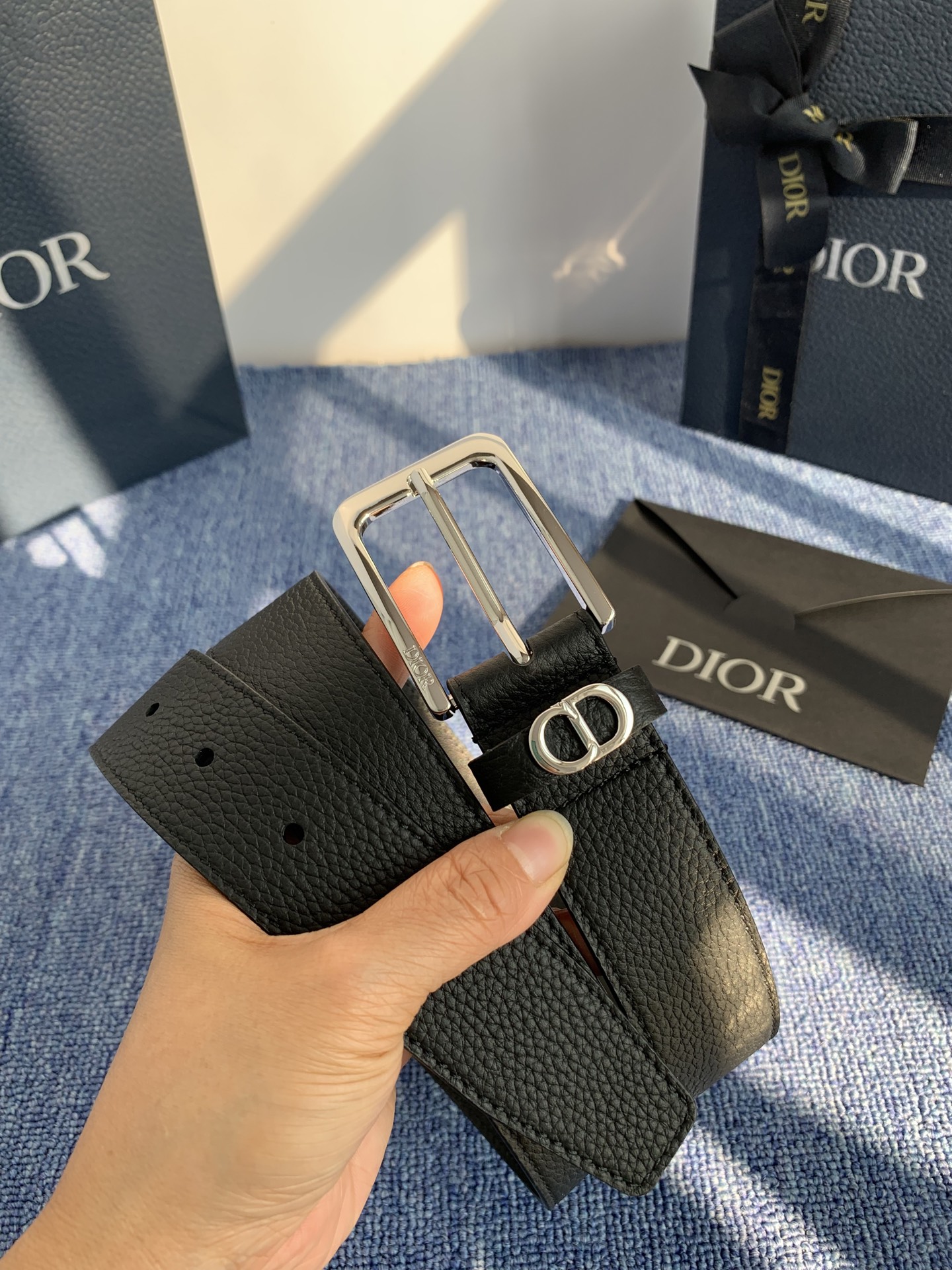 采用黑色粒面牛皮革精心制作，饰以镌刻有 Dior 的针扣和黑色金属覆层铜合金 CD Icon 标志腰带环