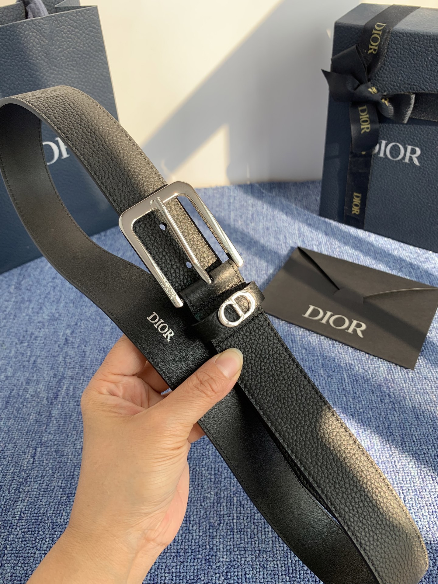 采用黑色粒面牛皮革精心制作，饰以镌刻有 Dior 的针扣和黑色金属覆层铜合金 CD Icon 标志腰带环