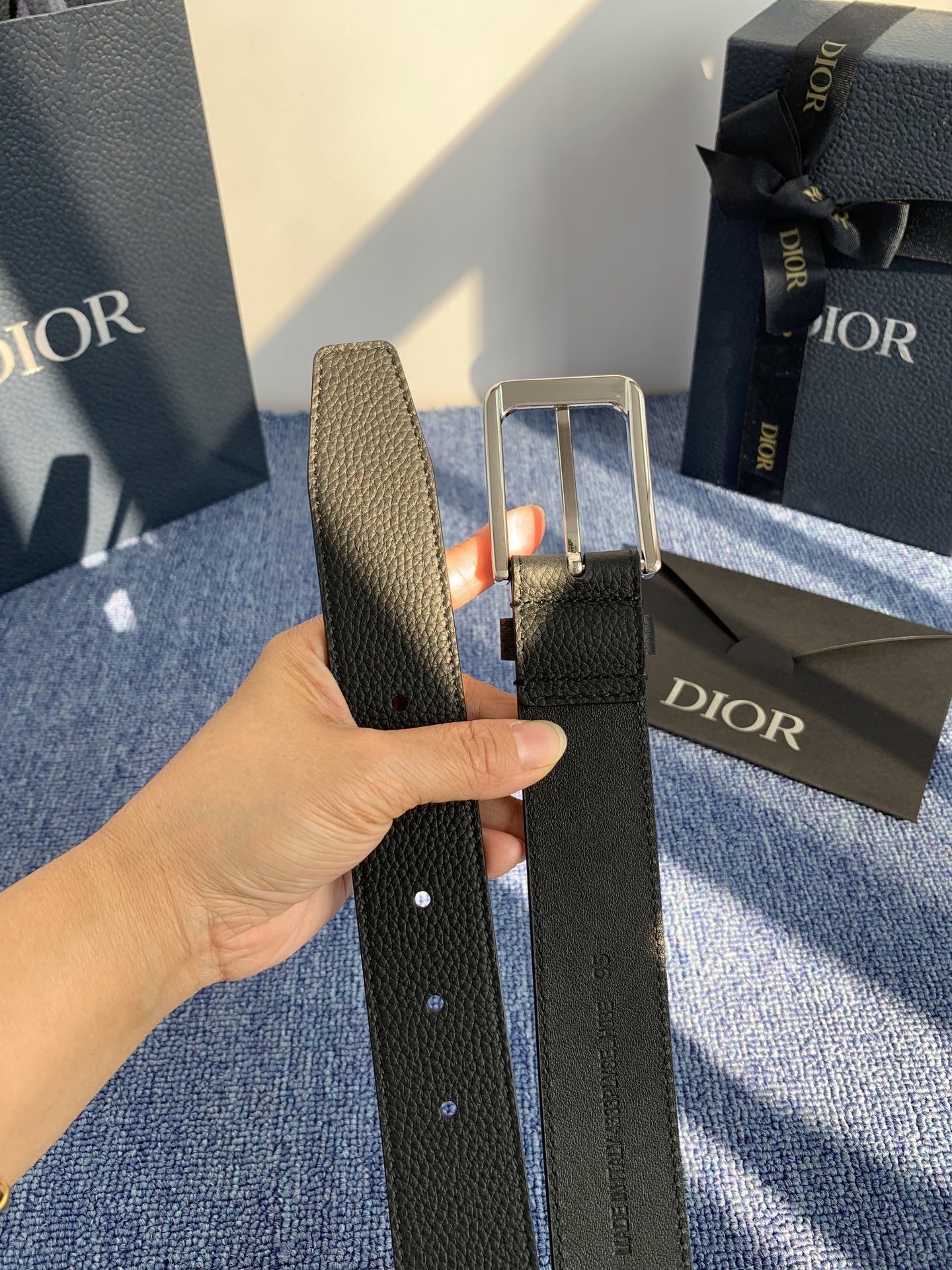 采用黑色粒面牛皮革精心制作，饰以镌刻有 Dior 的针扣和黑色金属覆层铜合金 CD Icon 标志腰带环