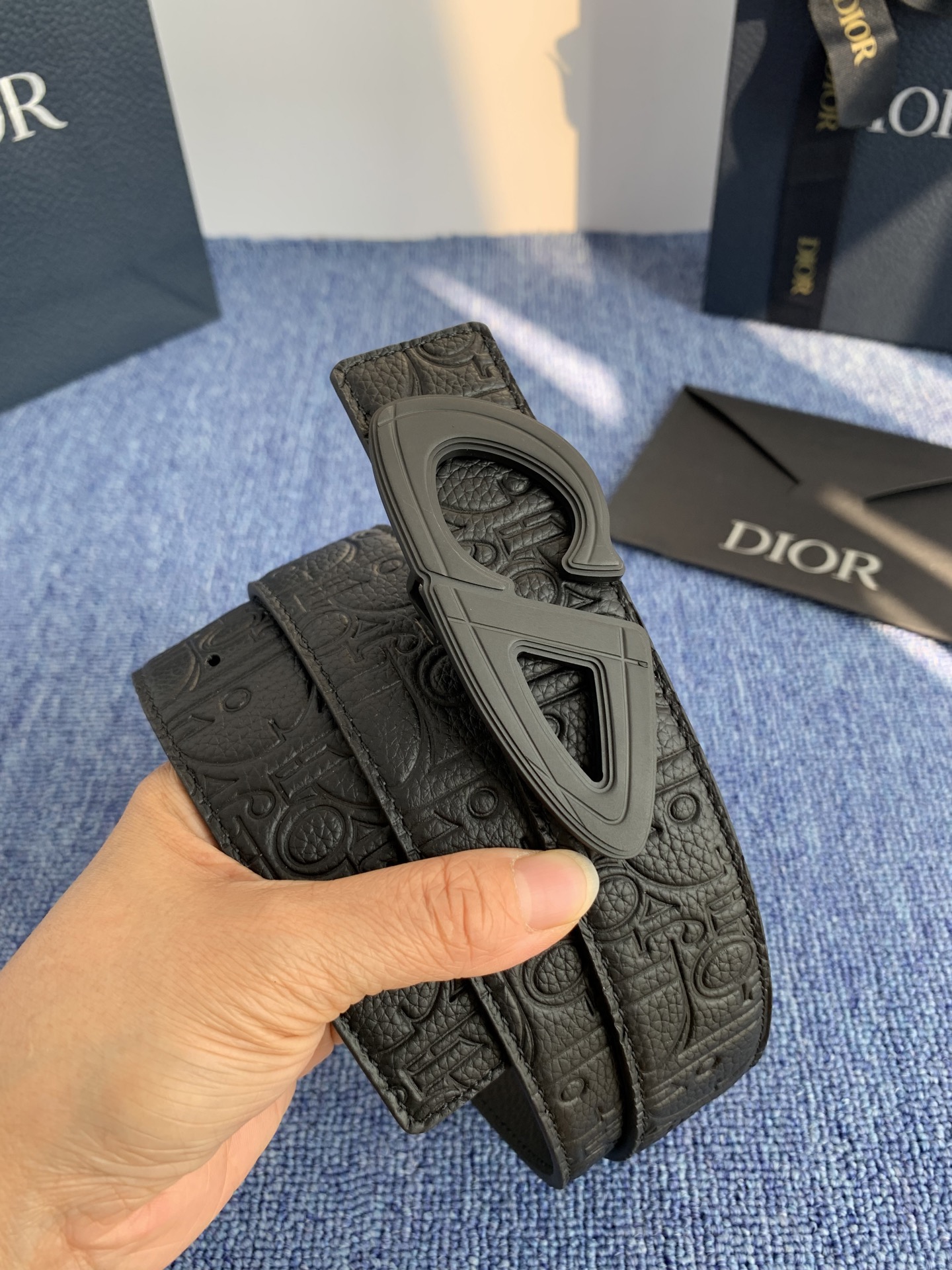 采用黑色粒面牛皮革精心制作，饰以镌刻有 Dior 的针扣和黑色金属覆层铜合金 CD Icon 标志腰带环