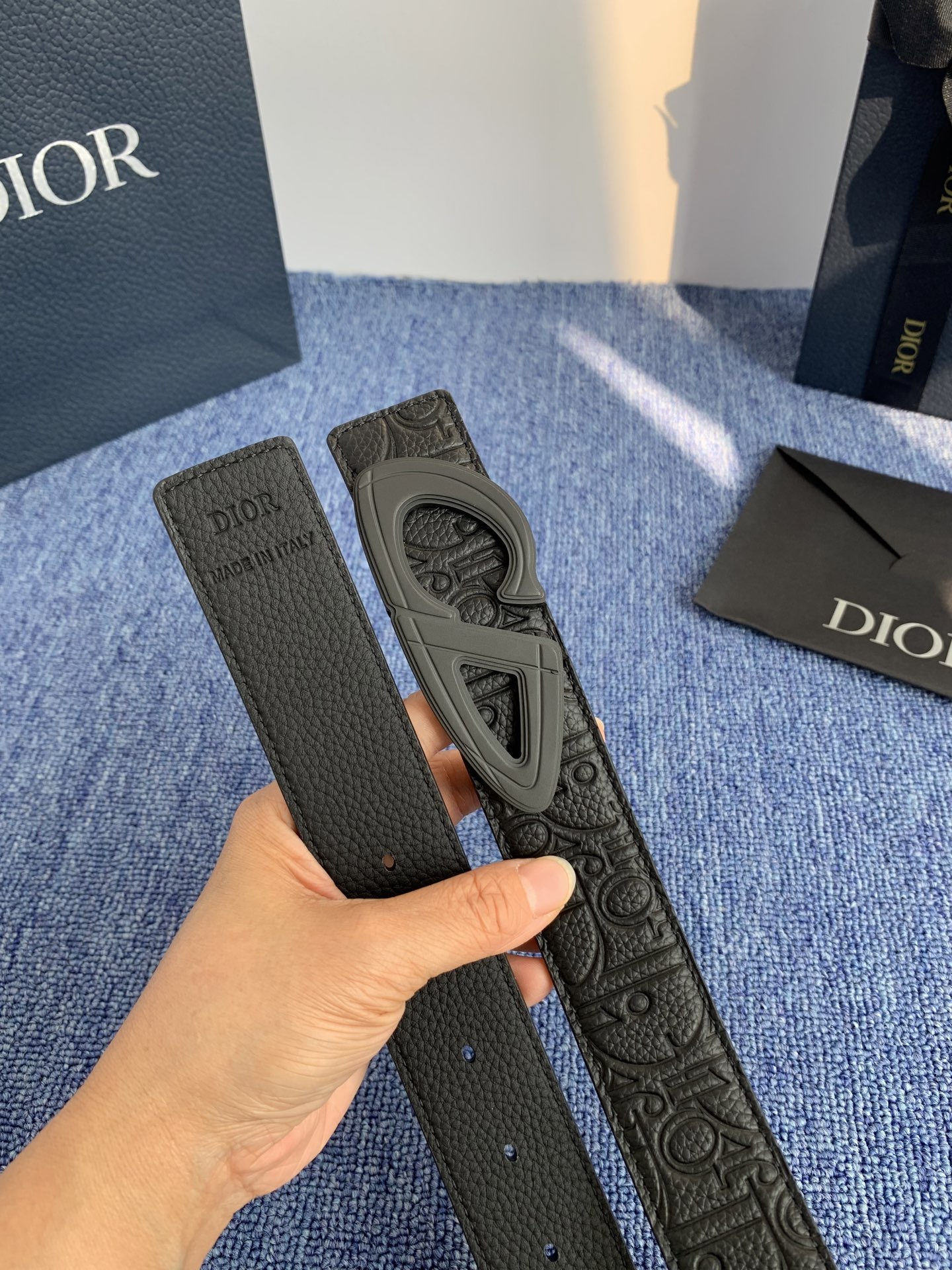 采用黑色粒面牛皮革精心制作，饰以镌刻有 Dior 的针扣和黑色金属覆层铜合金 CD Icon 标志腰带环