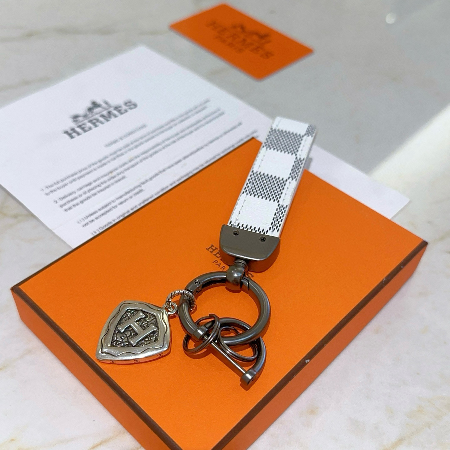 Pingente Hermes H Shield Key Charm Branco e cinza escuro em lona revestida de bronze e metal em tom prateado antigo 10 cm de comprimento total
