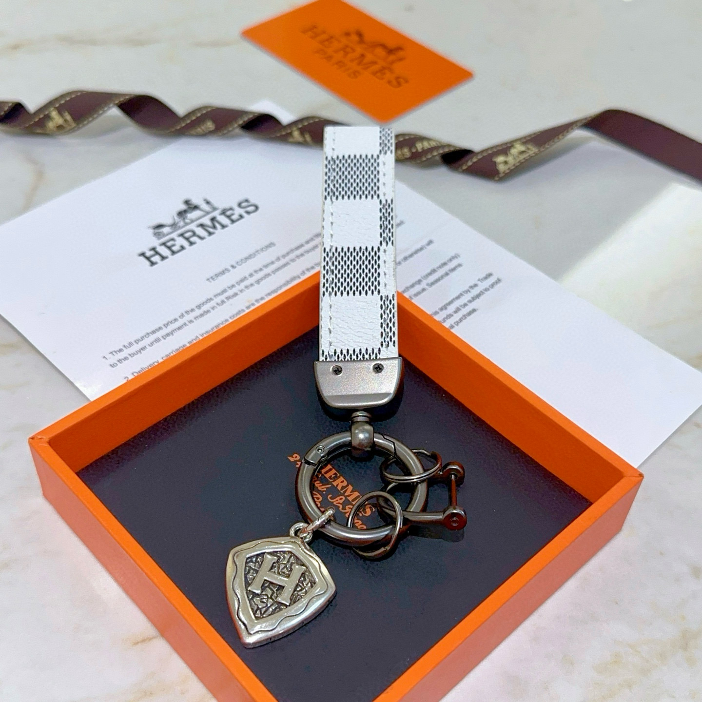 Pingente Hermes H Shield Key Charm Branco e cinza escuro em lona revestida de bronze e metal em tom prateado antigo 10 cm de comprimento total