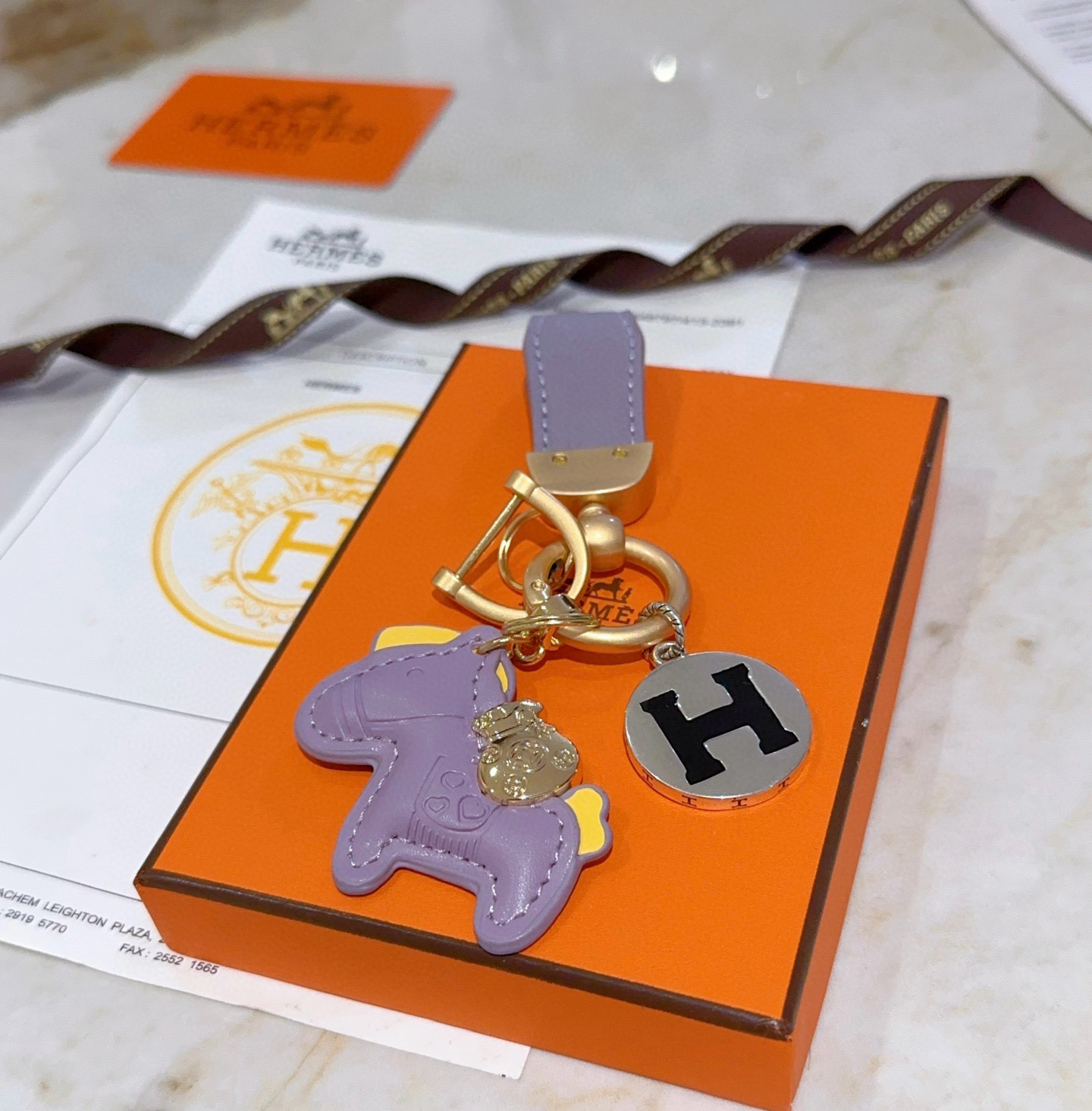 Hermes Rodeo Horse H Logo Key Charm pendant matte gold metal lavender purple leather silver-tone metal with black enamel H yellow leather accents 8cm total length