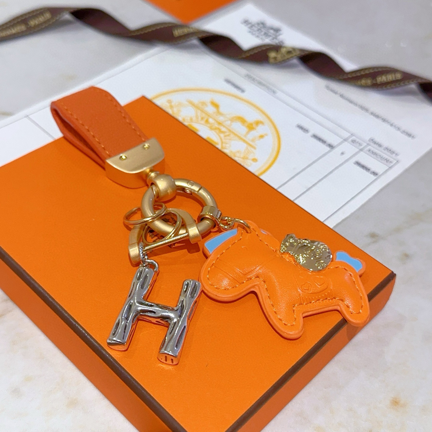 Pendentif Hermes Rodeo Pegase H Logo Key Charm Cuir orange avec accents bleu clair Quincaillerie en métal doré et argenté Longueur totale 8 cm