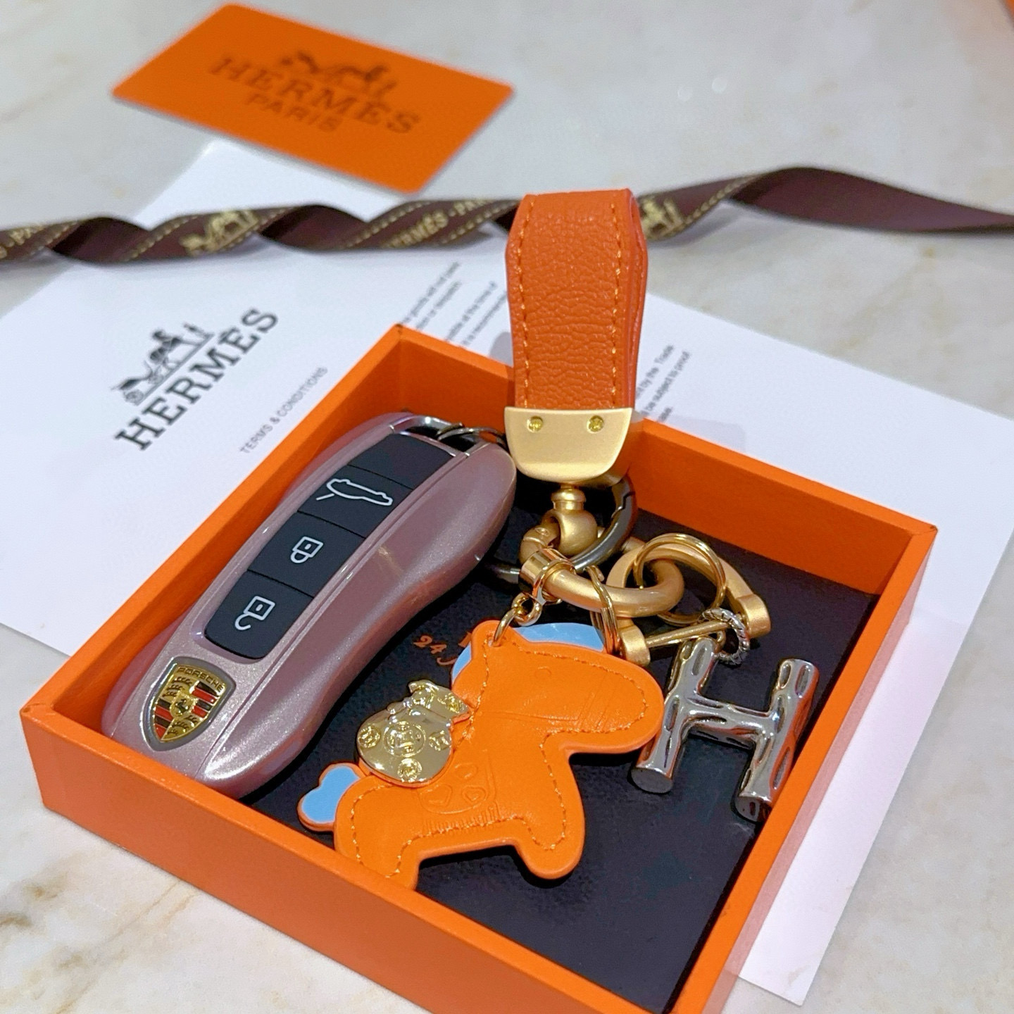 Pendentif Hermes Rodeo Pegase H Logo Key Charm Cuir orange avec accents bleu clair Quincaillerie en métal doré et argenté Longueur totale 8 cm