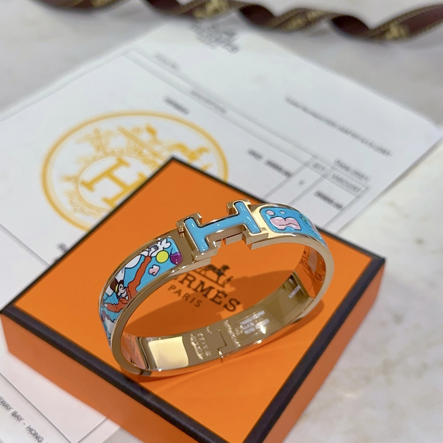 Hermes Clic Clac H bracelet Rose gold plated metal with light blue enamel featuring multicolor cartoon print PM