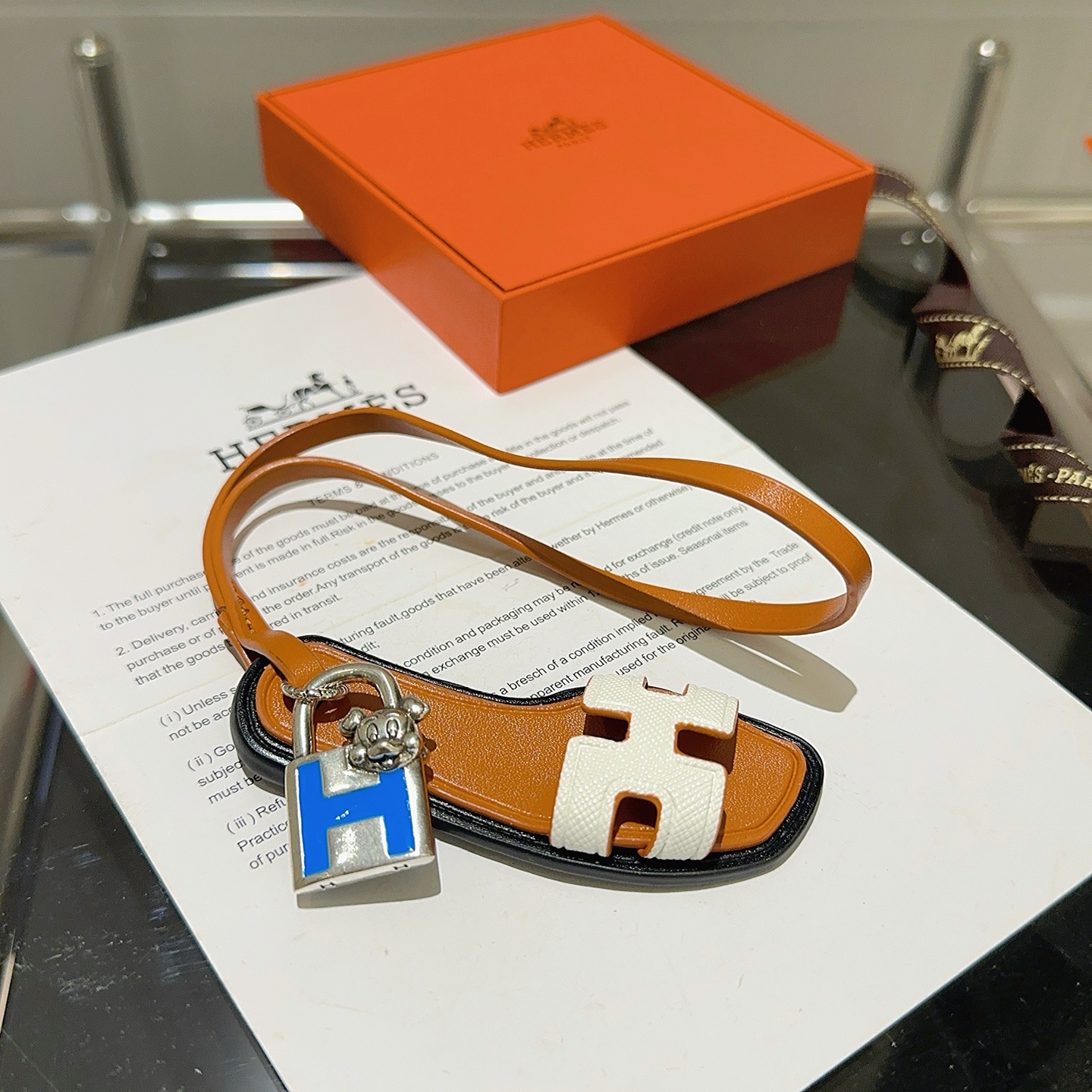 Hermes Oran Sandal Charm pendant tan leather white Epsom leather silver-tone metal blue enamel black edge trim 12cm strap length