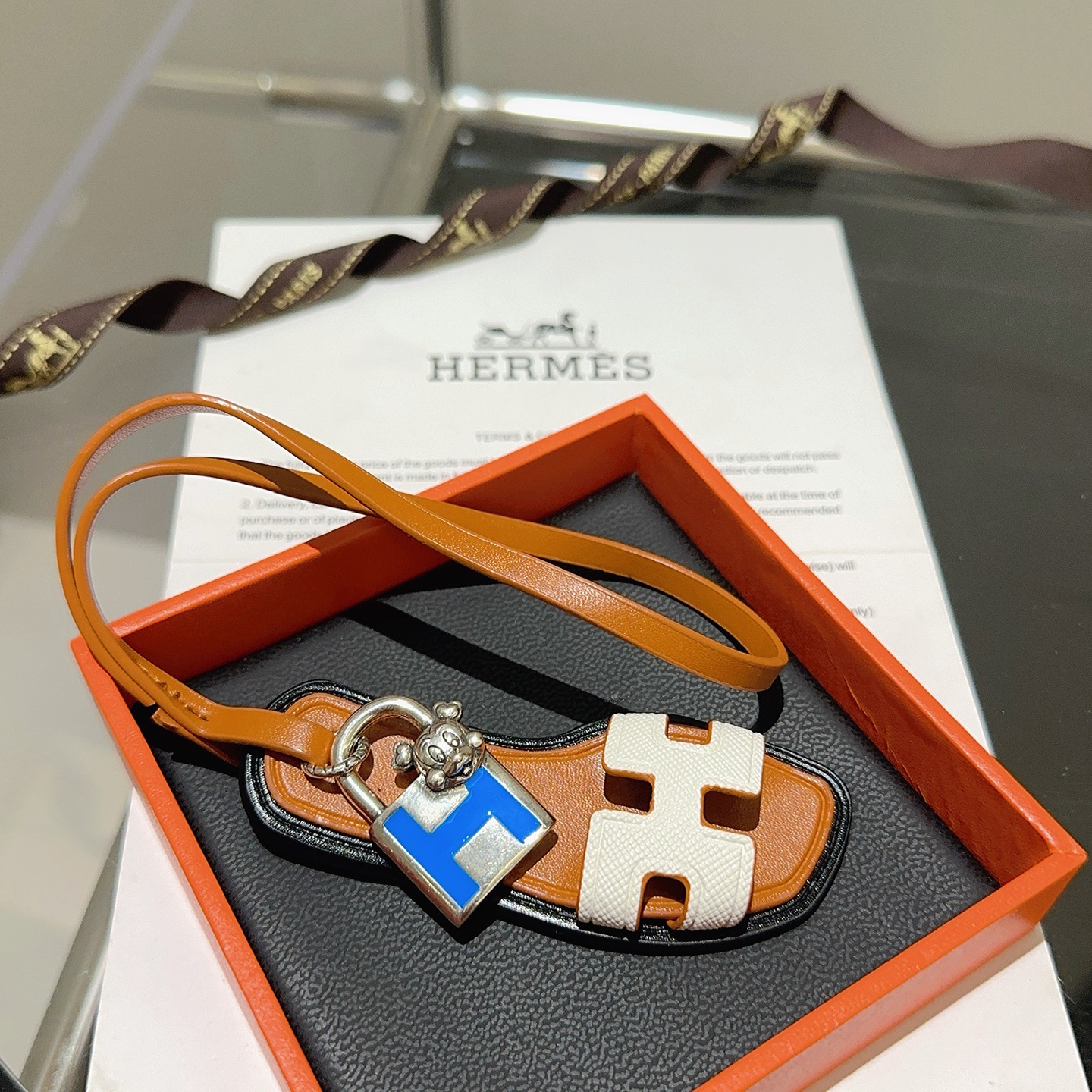 Hermes Oran Sandal Charm pendant tan leather white Epsom leather silver-tone metal blue enamel black edge trim 12cm strap length