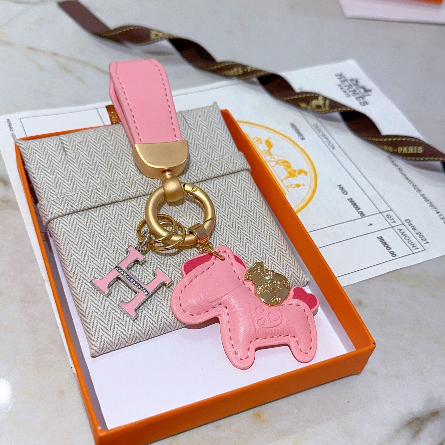 Chaveiro com logotipo Hermes Rodeo H Pingente de couro rosa com metal dourado esmalte rosa Pingente H com detalhes em cristal transparente 10 cm de comprimento total