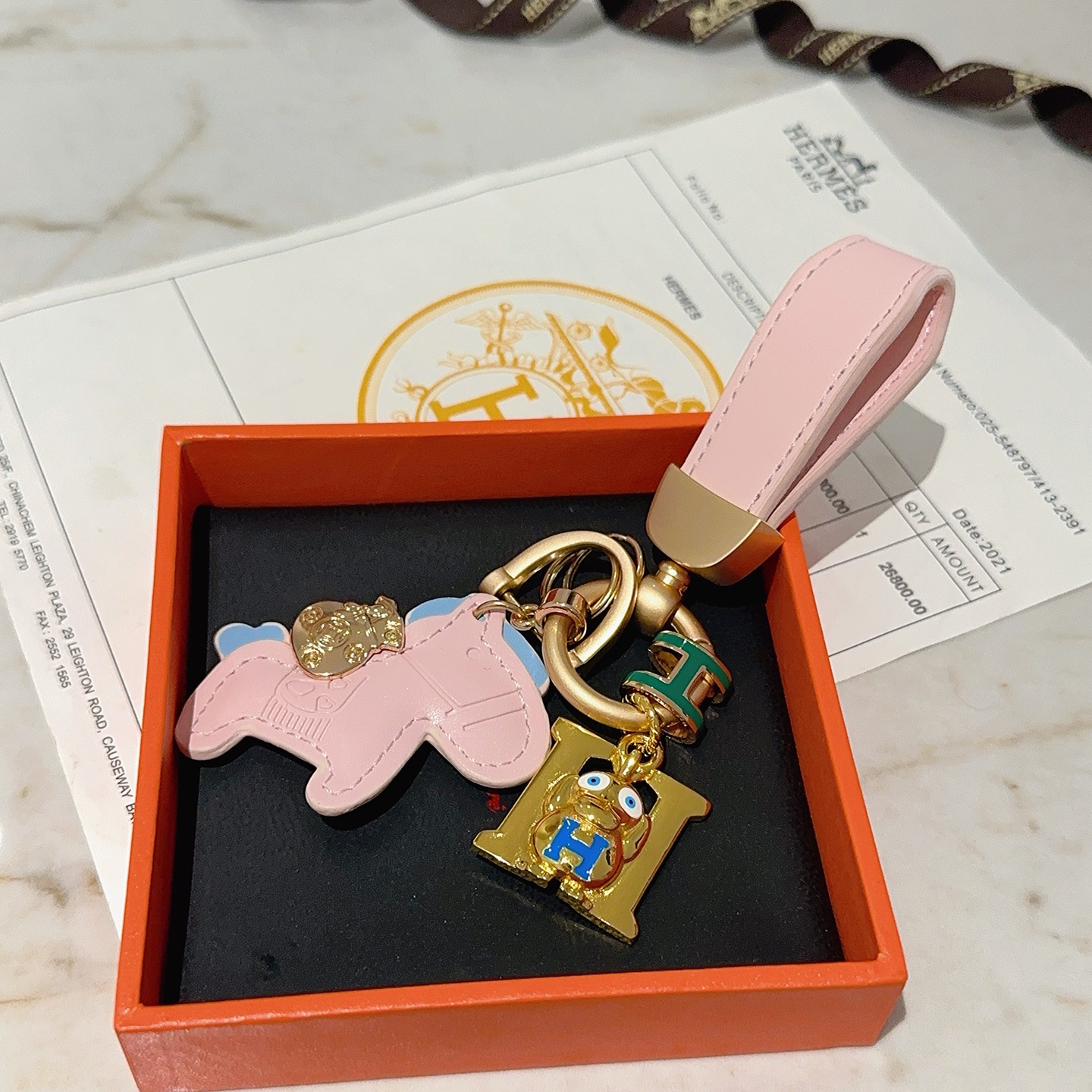 Hermes Rodeo H Logo Cartoon Charm Chaveiro pingente Couro rosa com detalhes em azul claro metal dourado detalhes em esmalte verde e azul 10 cm de comprimento total