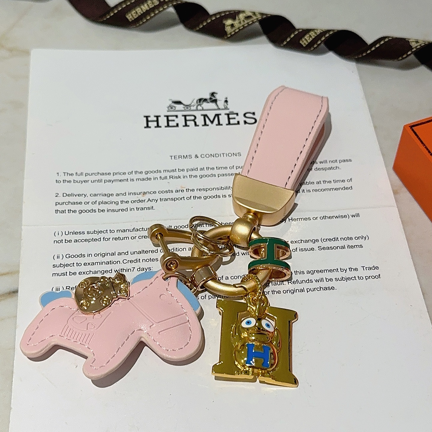 Hermes Rodeo H Logo Cartoon Charm Chaveiro pingente Couro rosa com detalhes em azul claro metal dourado detalhes em esmalte verde e azul 10 cm de comprimento total