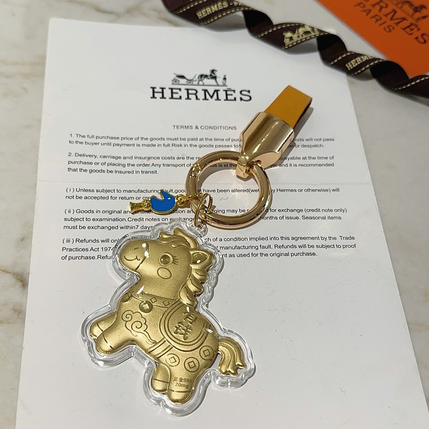 Pendentif porte-clés Hermes Lucky Horse Charm Métal doré avec bracelet en cuir orange accent en émail bleu boîtier de protection transparent sur breloque cheval doré Longueur totale 9 cm