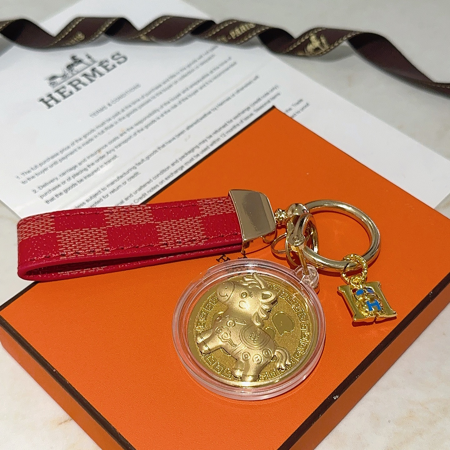 Pendentif porte-clés Hermes Lucky Horse Fu Charm Bracelet en toile enduite à carreaux rouges Quincaillerie en métal doré Médaillon doré en émail bleu Breloque H boîtier de médaillon de protection transparent 10 cm de longueur totale