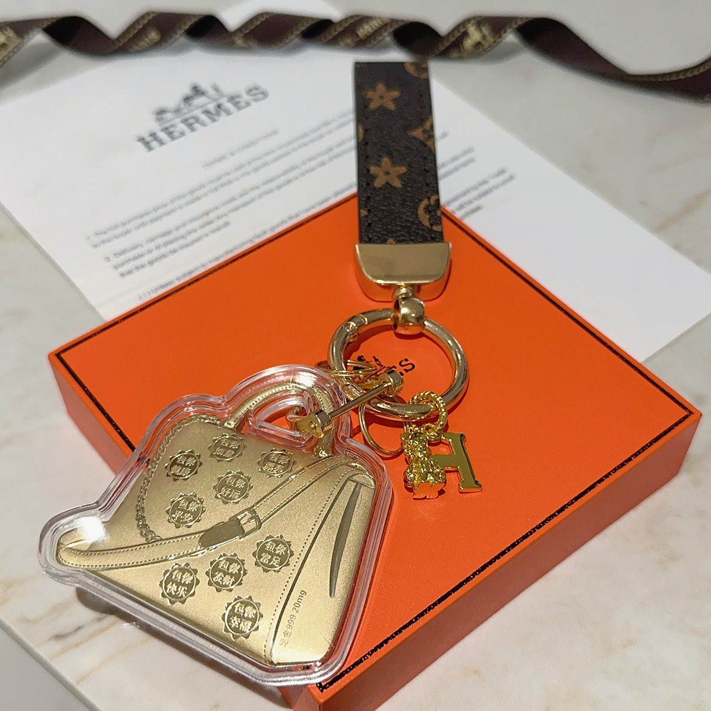 Hermes Bolide Bag Charm Porte-clés pendentif Métal doré monogramme marron foncé toile enduite boîtier en acrylique transparent longueur totale 12 cm
