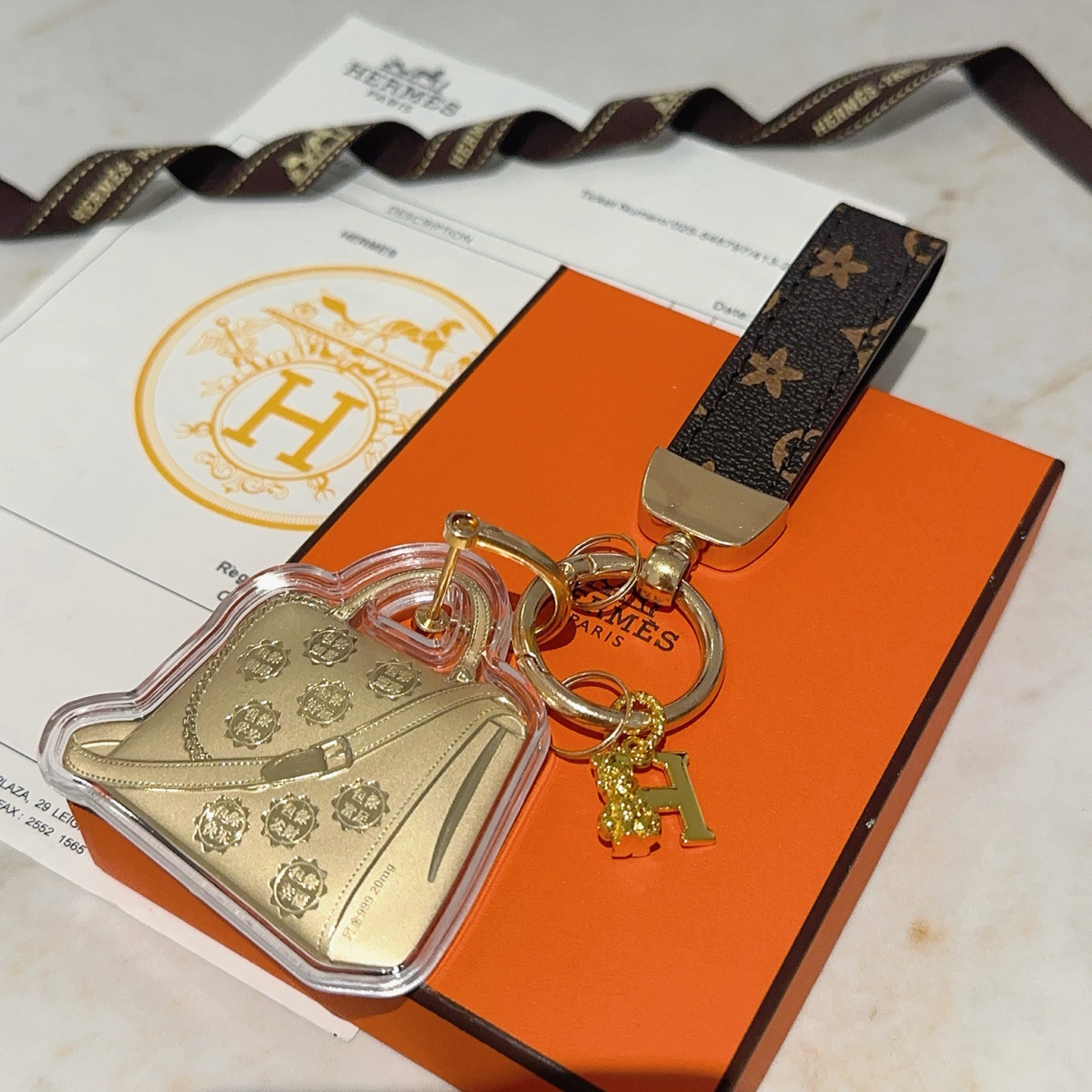 Hermes Bolide Bag Charm Porte-clés pendentif Métal doré monogramme marron foncé toile enduite boîtier en acrylique transparent longueur totale 12 cm