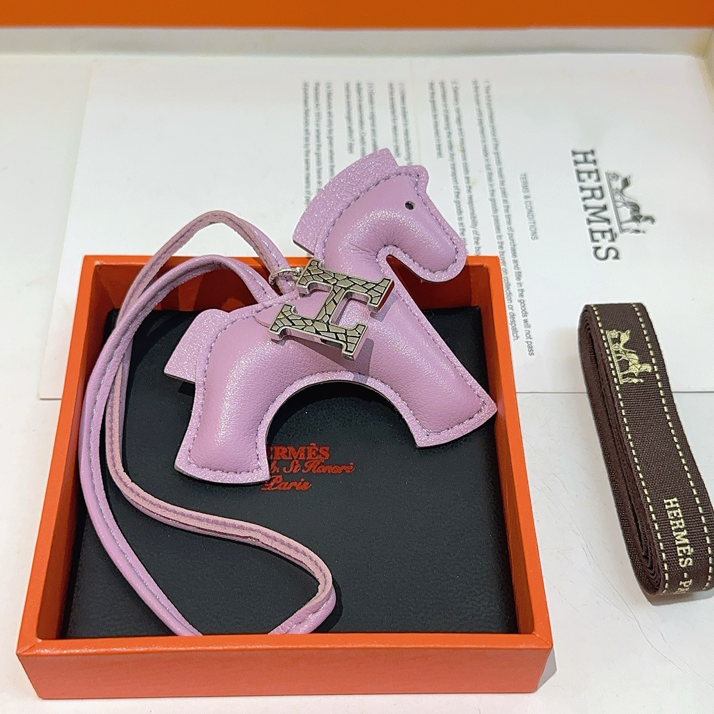 Charme de cavalo Hermes Rodeo Pegase com pingente de logotipo H Mauve Sylvestre couro roxo claro tom prateado textura rachada metal H hardware detalhe de olho preto Charme de 8 cm com pulseira de couro de 12 cm