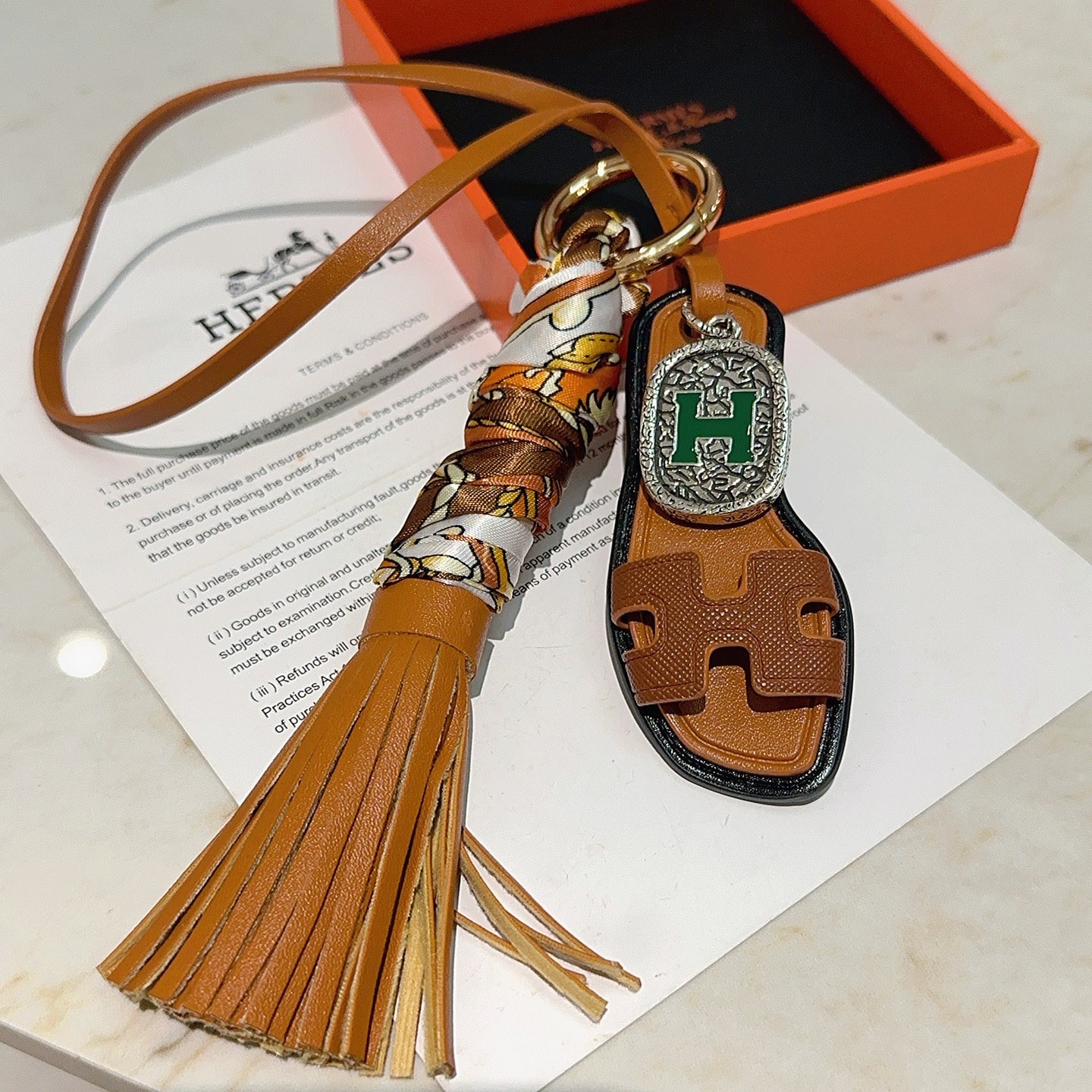 Hermes Oran Sandalo Borsa con nappa Ciondolo con ciondolo Metallo color oro Pelle marrone chiaro Seta stampata multicolore Hardware color argento con dettaglio H in smalto verde Finiture in pelle nera Lunghezza cinturino 18 cm