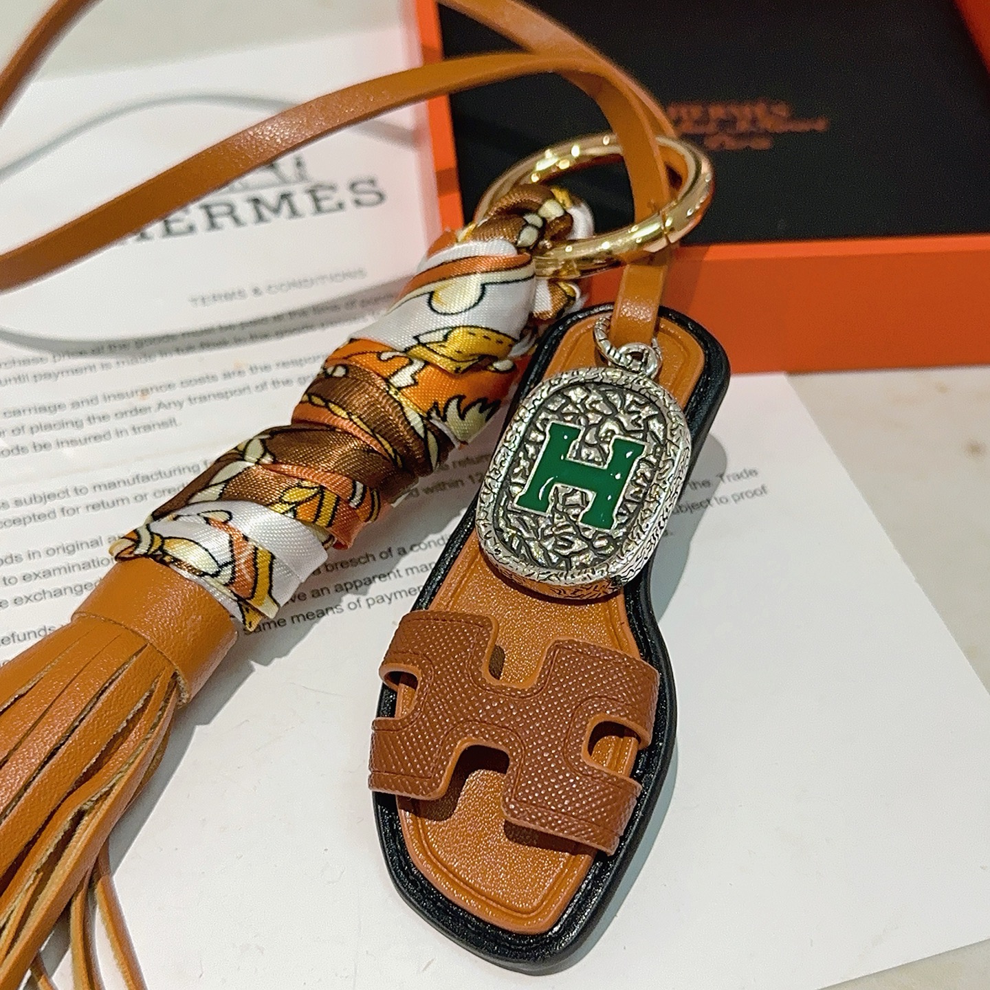Hermes Oran Sandalo Borsa con nappa Ciondolo con ciondolo Metallo color oro Pelle marrone chiaro Seta stampata multicolore Hardware color argento con dettaglio H in smalto verde Finiture in pelle nera Lunghezza cinturino 18 cm