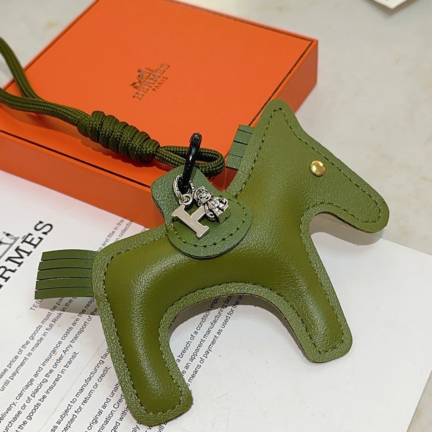 Ciondolo portachiavi Hermes Rodeo Horse Charm in pelle verde oliva con hardware in metallo argentato antico e rivetto dorato, lunghezza cordino 12 cm