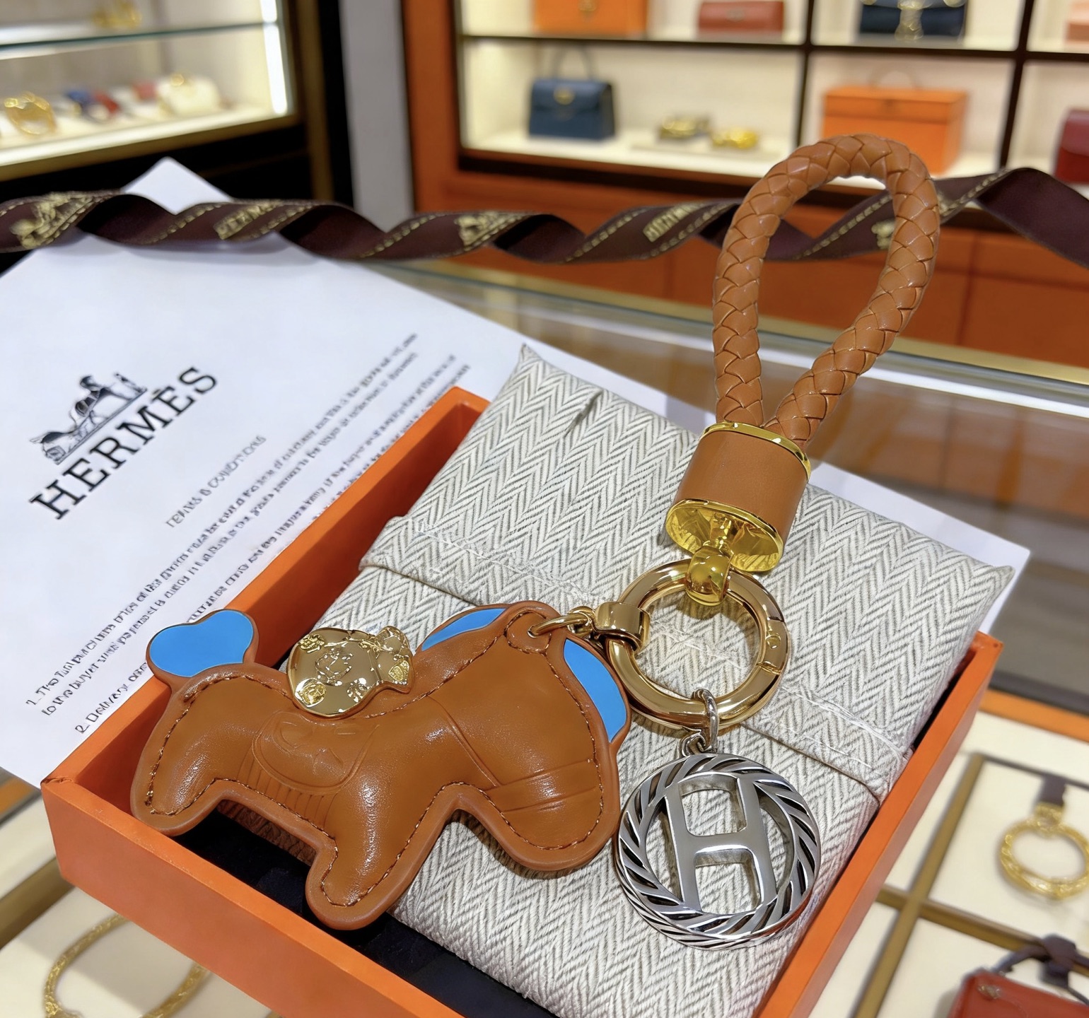 Pendentif Hermes Rodeo Braided Strap Key Charm Cuir marron doré avec des accents bleu ciel Quincaillerie en métal doré et argenté Longueur totale de 12 cm
