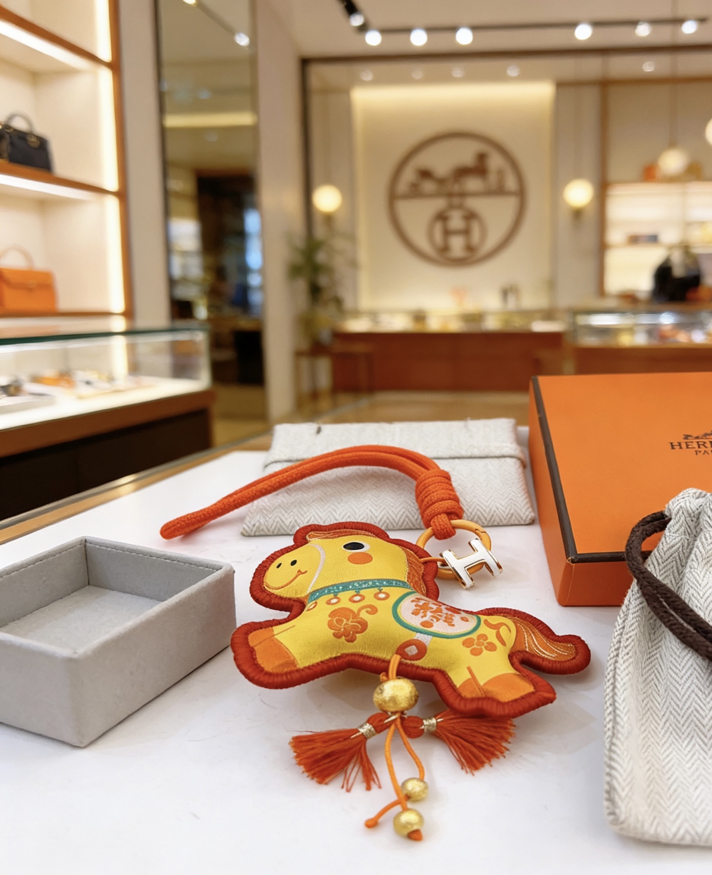Hermes Rodeo Horse Charm pendant Yellow fabric with orange trim orange cord gold-tone metal hardware white enamel H detail red tassels 12cm
