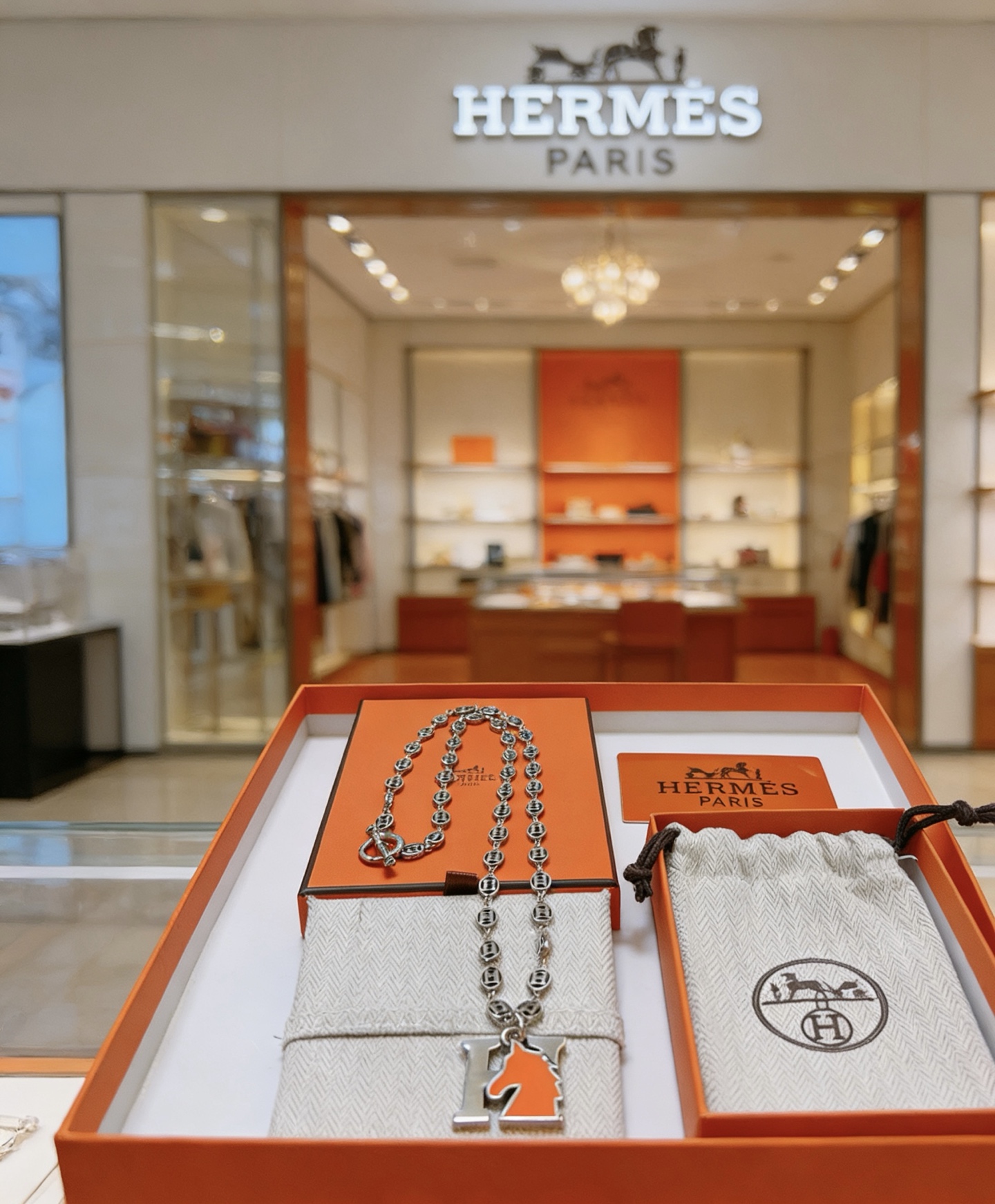 Collier pendentif Hermes Cheval H Métal argenté et émail orange 45cm