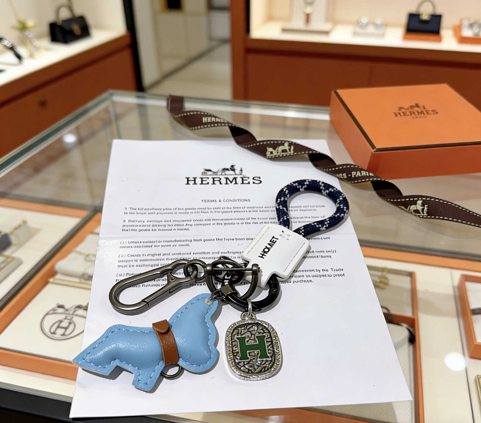 Hermes H Logo Horse Charm Porte-clés pendentif Matériel en bronze à canon corde tressée bleu marine avec accents blancs étiquette en cuir blanc breloque cheval en cuir bleu clair avec bracelet en cuir marron breloque en argent antique avec émail H vert longueur totale 10 cm