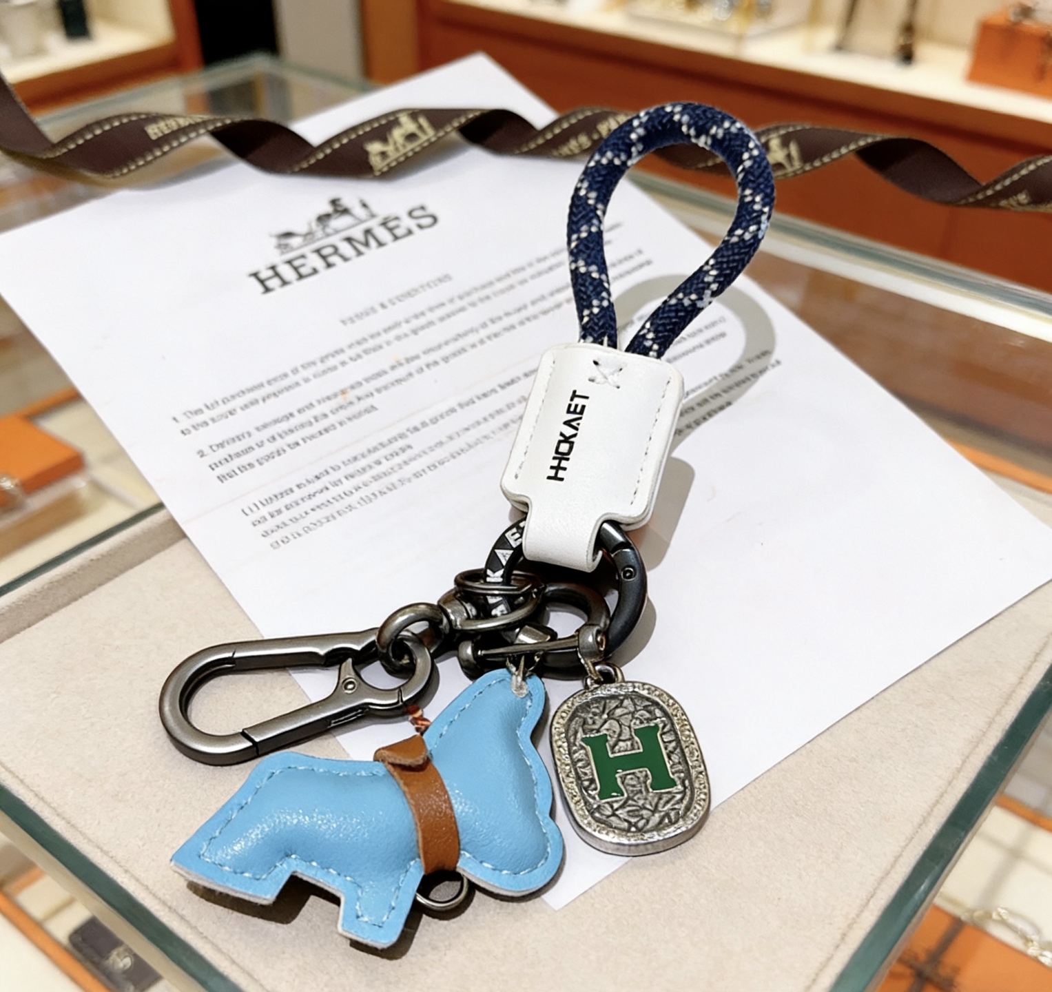 Hermes H Logo Horse Charm Porte-clés pendentif Matériel en bronze à canon corde tressée bleu marine avec accents blancs étiquette en cuir blanc breloque cheval en cuir bleu clair avec bracelet en cuir marron breloque en argent antique avec émail H vert longueur totale 10 cm
