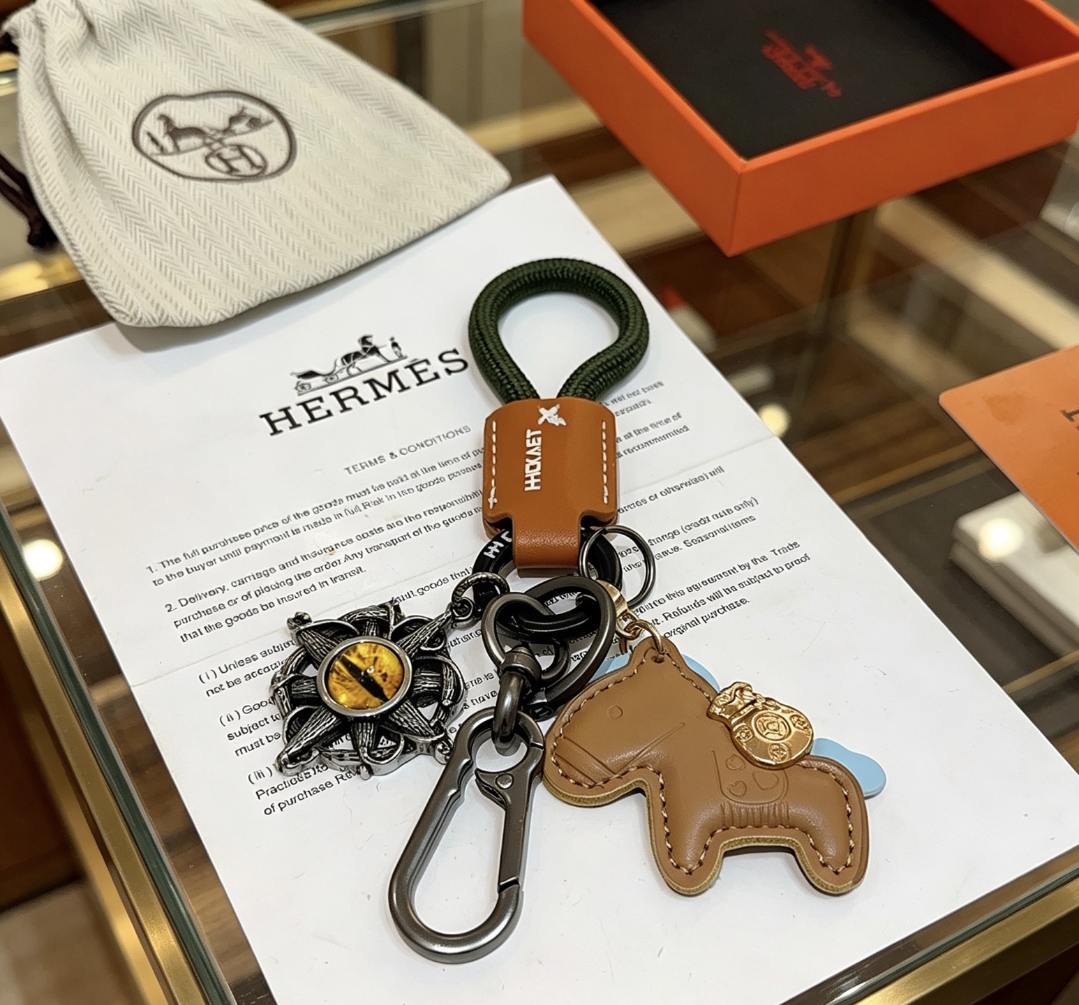 Hermes Rodeo Horse Charm Portachiavi Ciondolo in pelle marrone chiaro Cavo intrecciato verde scuro Hardware in canna di fucile Accento in metallo color oro Pietra gialla occhio di gatto Supporto azzurro 10 cm Lunghezza totale