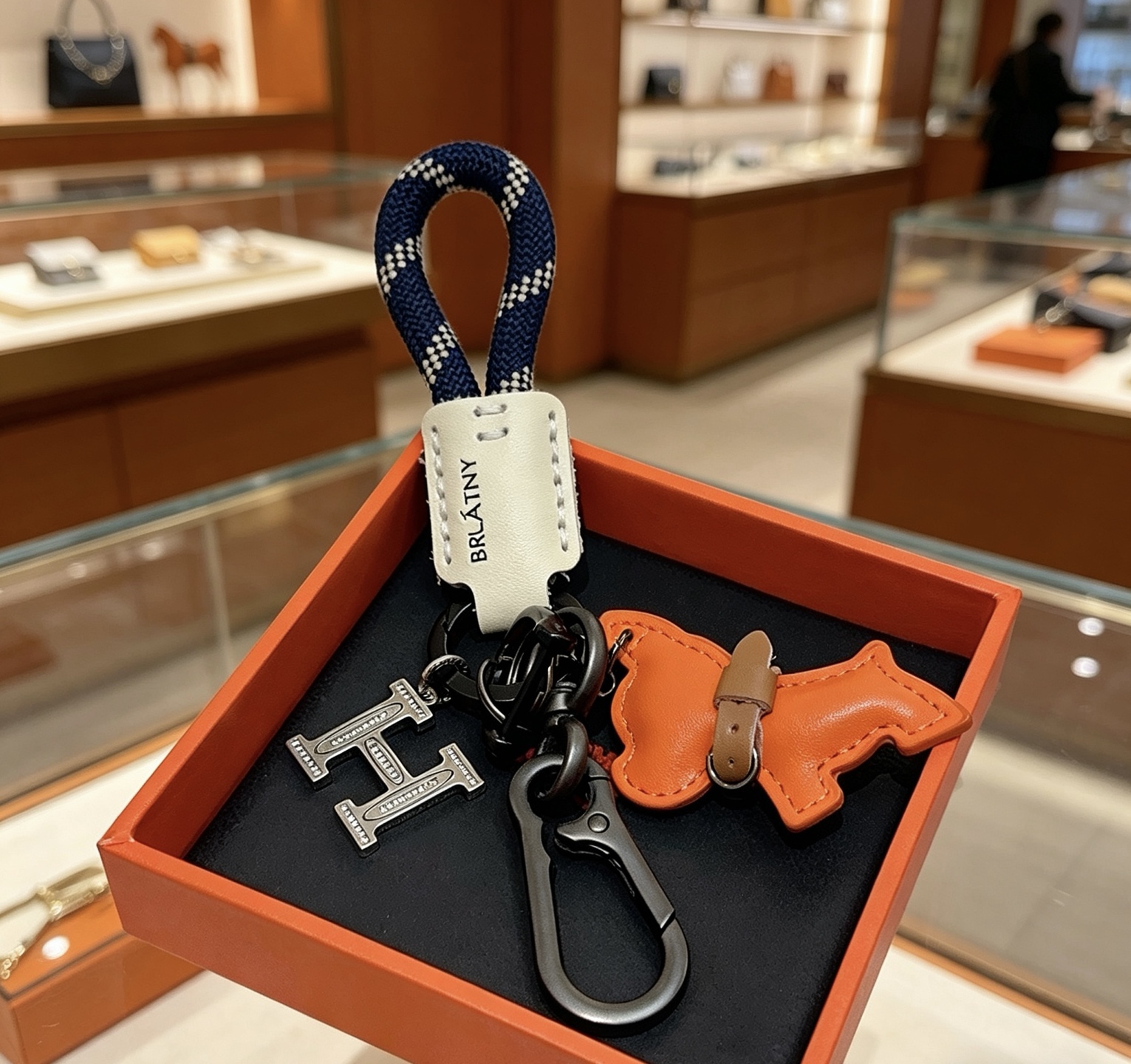 Hermes BRLATNY Puppy H Charm Keychain pendant Gunmetal black hardware orange leather puppy charm off-white leather tag navy blue with white woven rope brown leather collar detail 12cm total length