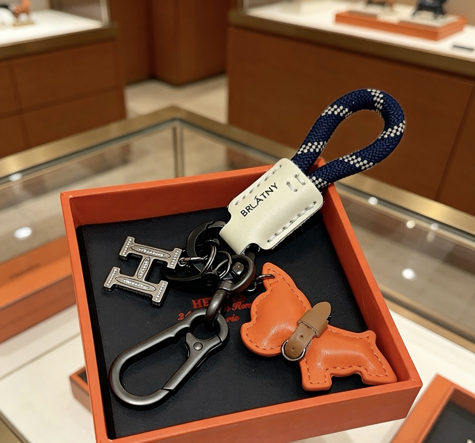 Hermes BRLATNY Puppy H Charm Keychain pendant Gunmetal black hardware orange leather puppy charm off-white leather tag navy blue with white woven rope brown leather collar detail 12cm total length