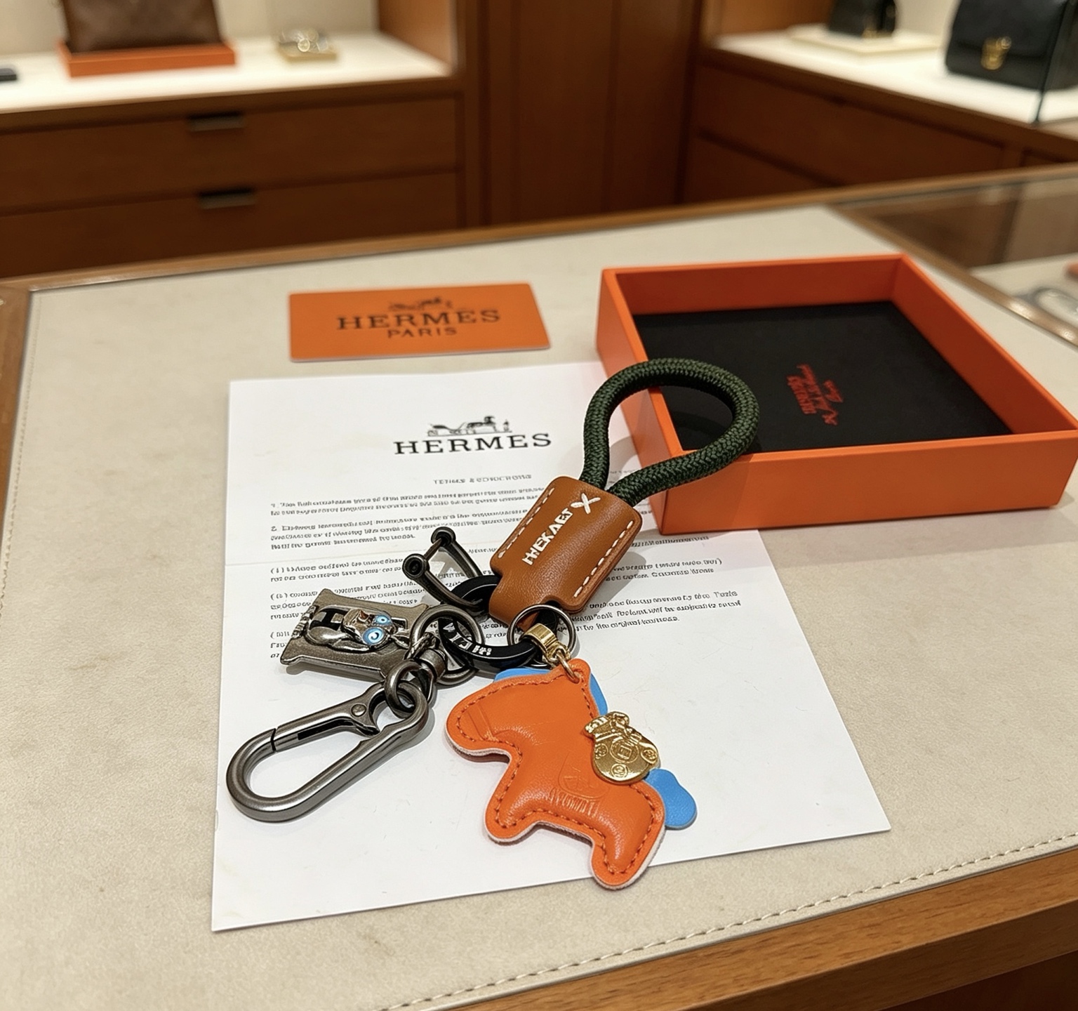 Hermes Rodeo Horse Charm Porte-clés pendentif Cuir orange avec accents bleus cuir marron cordon tressé vert foncé matériel en bronze à canon breloque en métal doré breloque H argentée avec détails en émail bleu longueur totale 12 cm