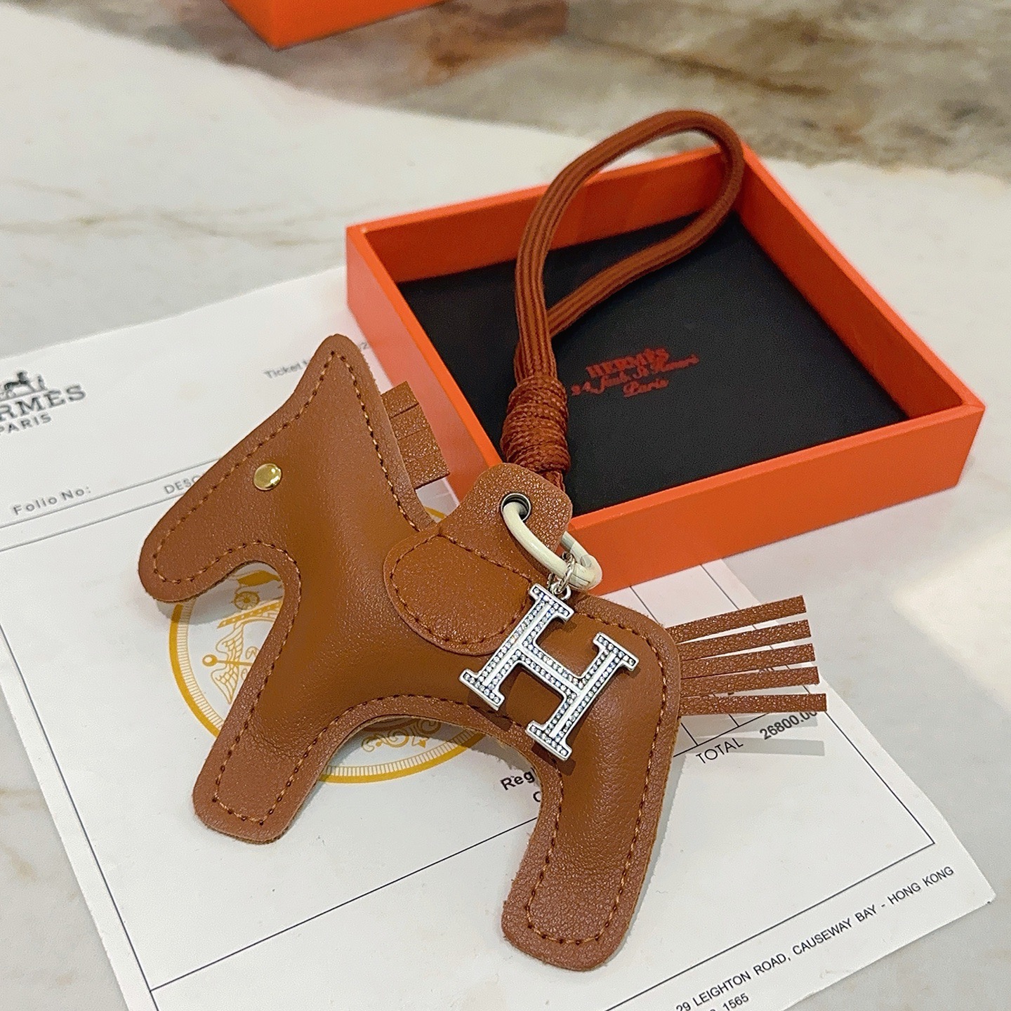 Breloque de sac à cheval Hermes Rodeo Pegase avec pendentif en cristal H Pendentif Cuir marron doré Métal argenté avec pavé de cristaux transparents Quincaillerie blanc cassé Cordon marron terre cuite Longueur totale de la breloque 12 cm Bracelet de cordon de 8 cm