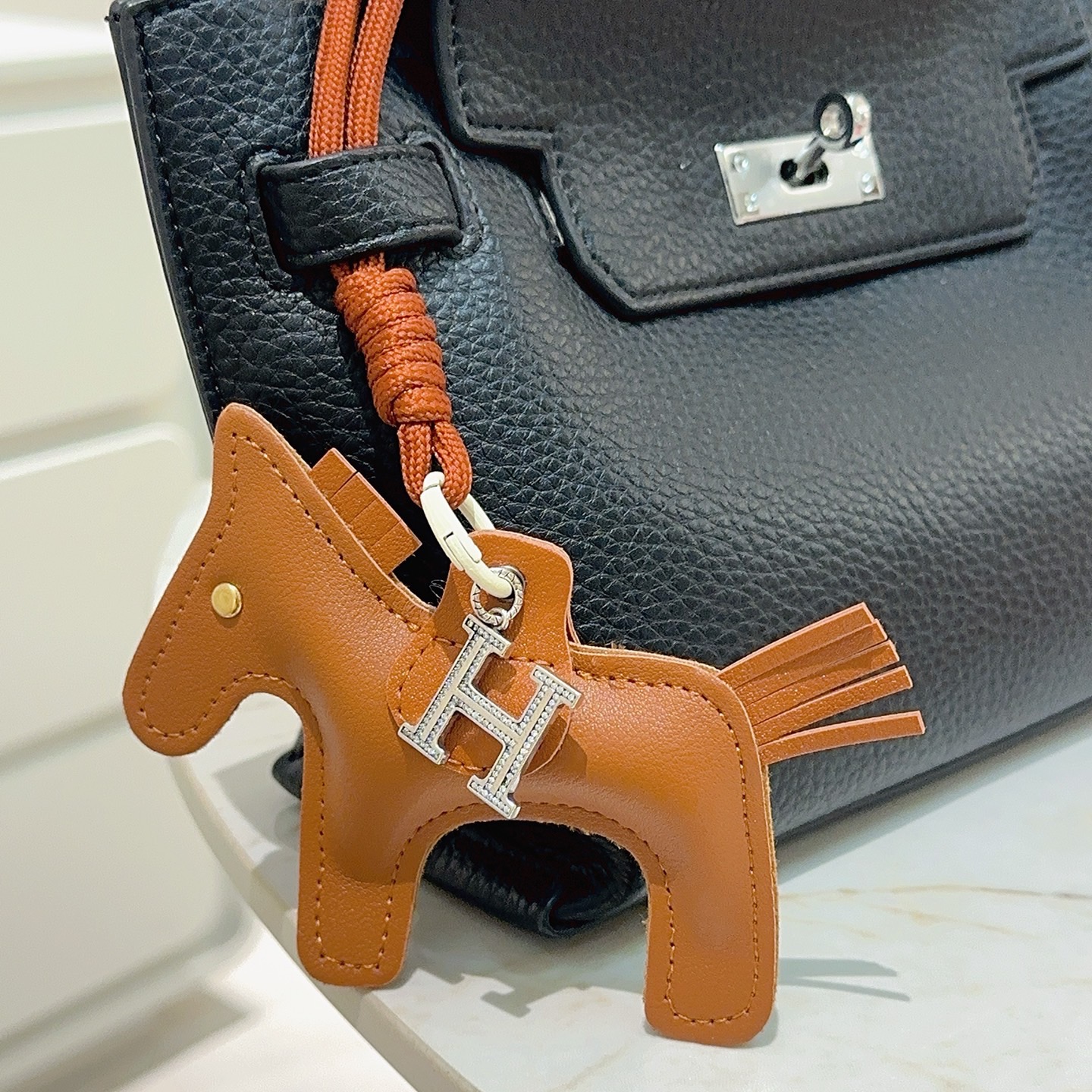 Breloque de sac à cheval Hermes Rodeo Pegase avec pendentif en cristal H Pendentif Cuir marron doré Métal argenté avec pavé de cristaux transparents Quincaillerie blanc cassé Cordon marron terre cuite Longueur totale de la breloque 12 cm Bracelet de cordon de 8 cm