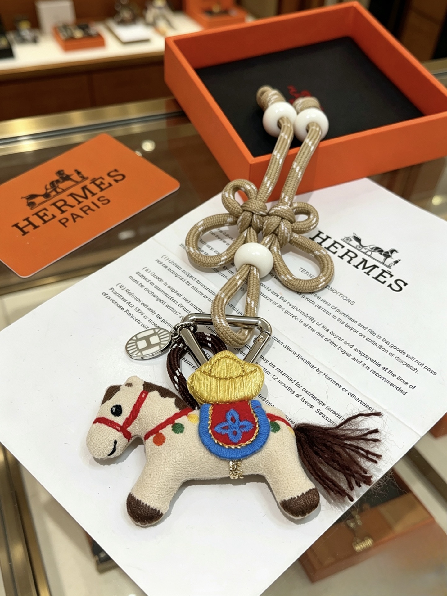 Hermes Rodeo Chinese Knot Horse Charm pendant palladium silver metal beige fabric horse with multicolor embroidery champagne gold woven cord with white resin beads 12cm total length