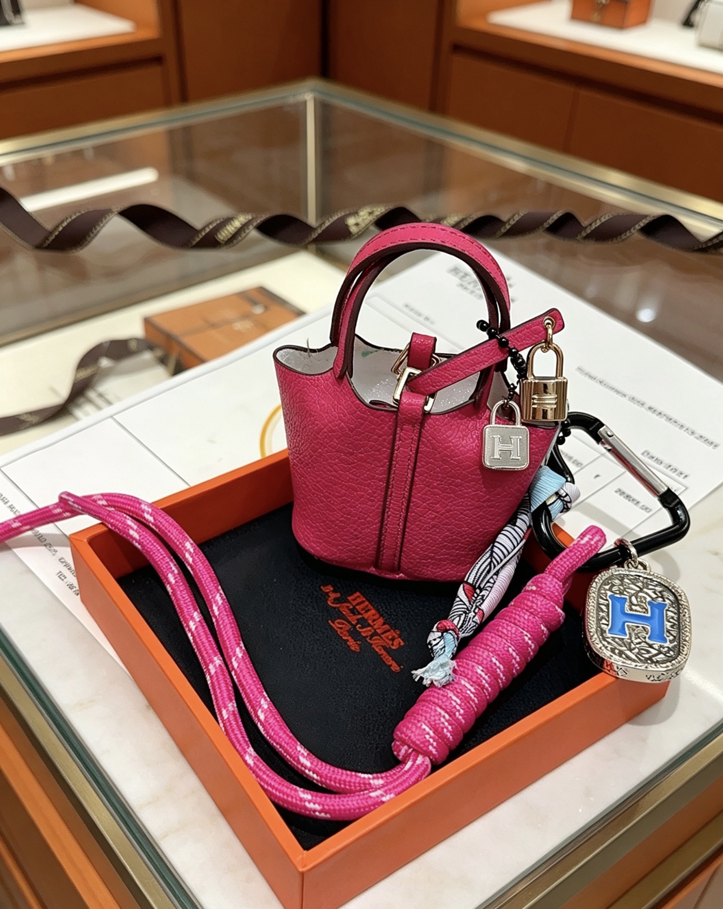 Pendentif Hermes Mini Picotin Lock Bag Charm Cuir grainé rose rose Quincaillerie en métal doré rose Métal argenté avec émail bleu Logo H Accent en twilly de soie imprimé multicolore Longueur totale 20 cm