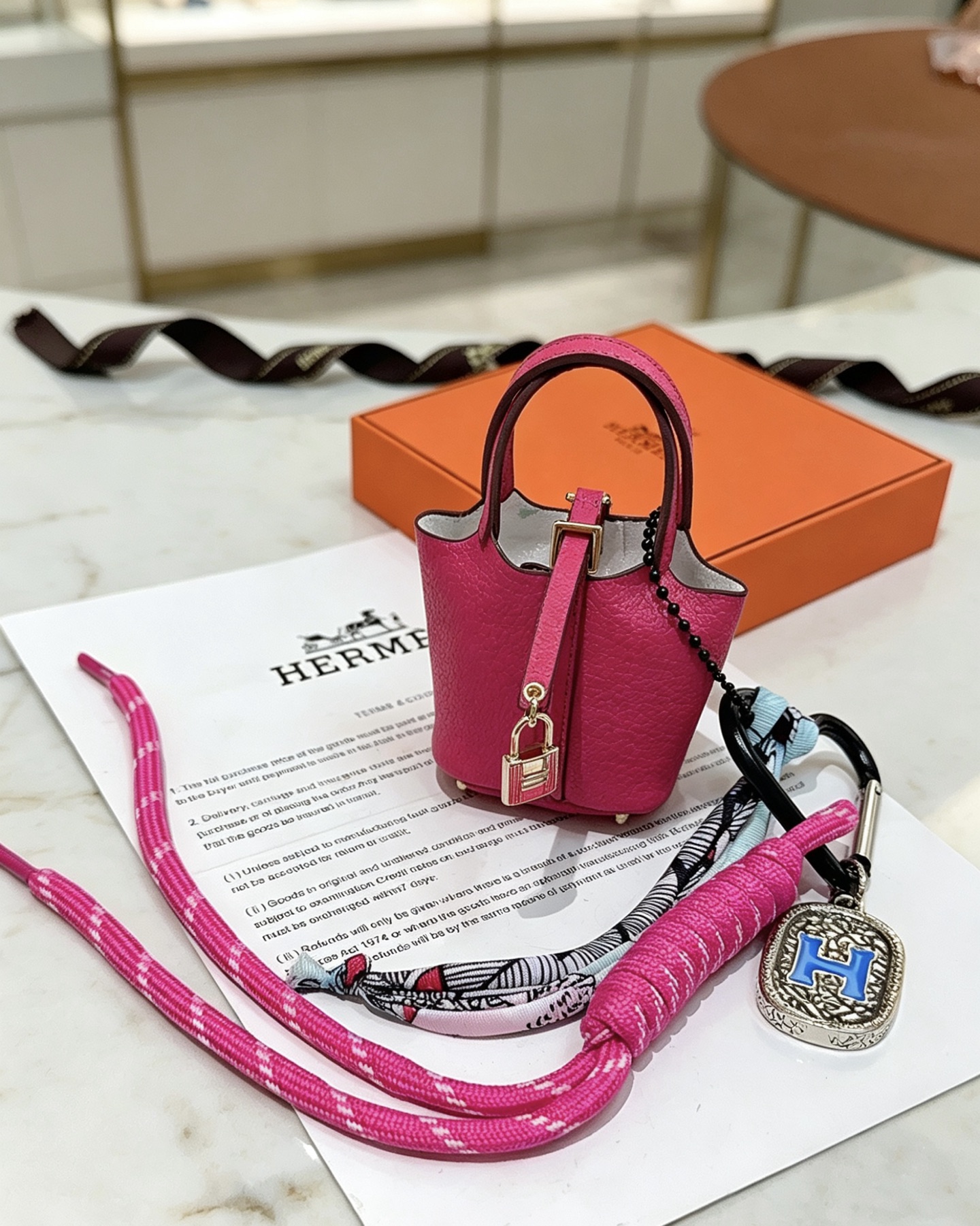 Pendentif Hermes Mini Picotin Lock Bag Charm Cuir grainé rose rose Quincaillerie en métal doré rose Métal argenté avec émail bleu Logo H Accent en twilly de soie imprimé multicolore Longueur totale 20 cm