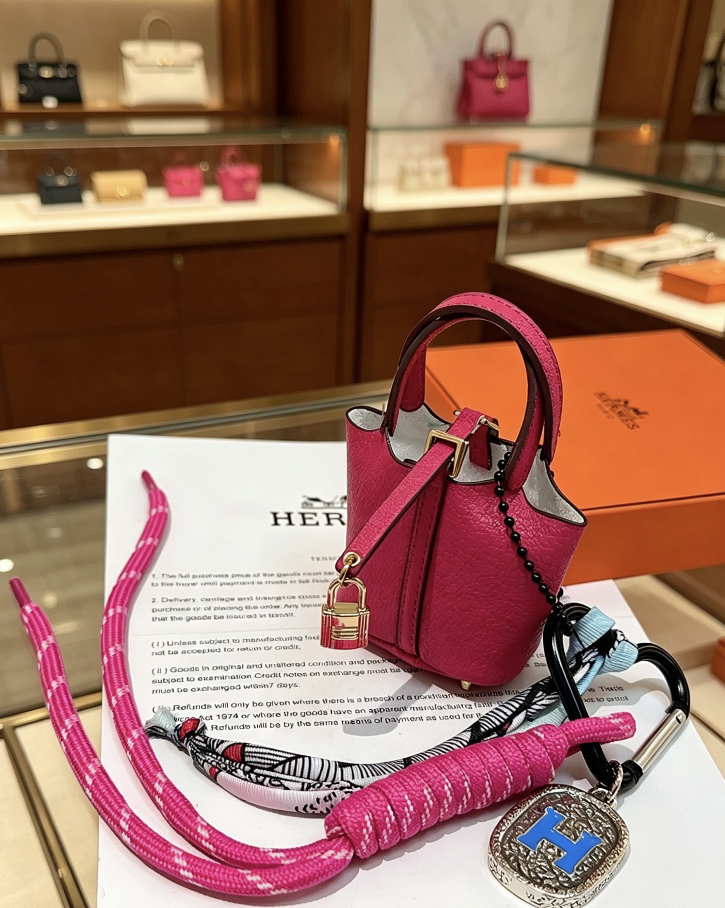Pendentif Hermes Mini Picotin Lock Bag Charm Cuir grainé rose rose Quincaillerie en métal doré rose Métal argenté avec émail bleu Logo H Accent en twilly de soie imprimé multicolore Longueur totale 20 cm