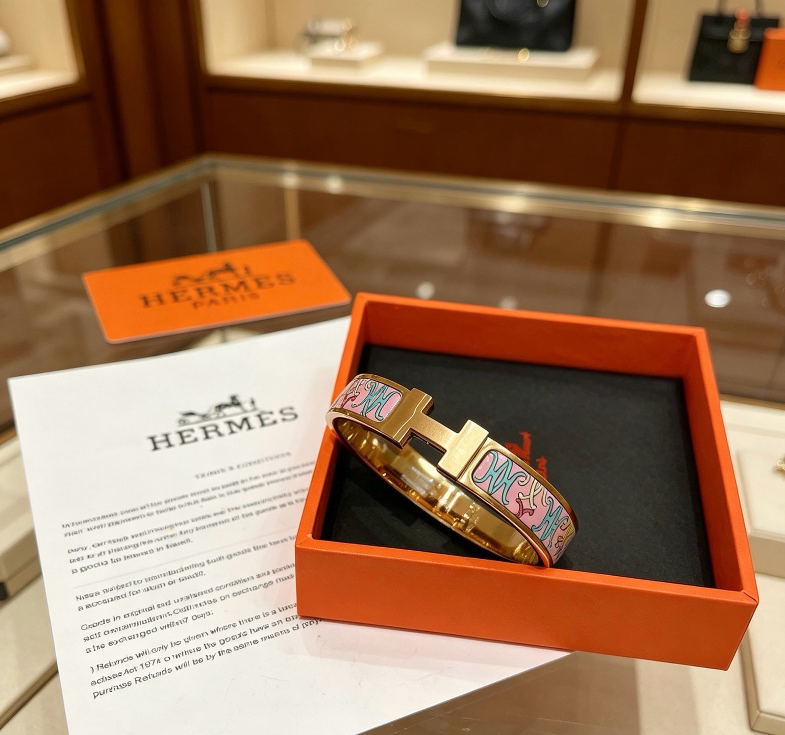 Bracelet Hermes Clic H en métal doré rose et émail rose à motifs décoratifs multicolores 17