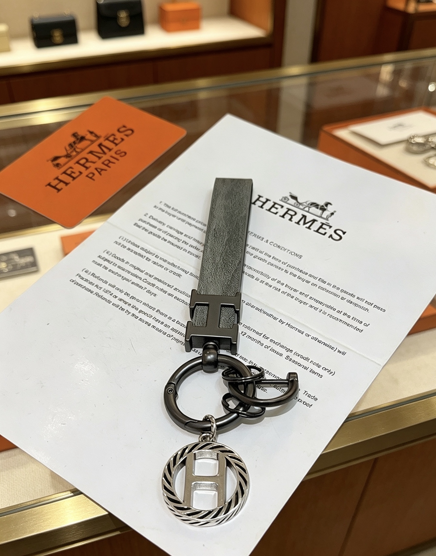 Hermes H Logo Leather Strap Keychain pendant Gunmetal gray metal matte gray leather strap silver-toned H charm with black striped detailing 10cm total length