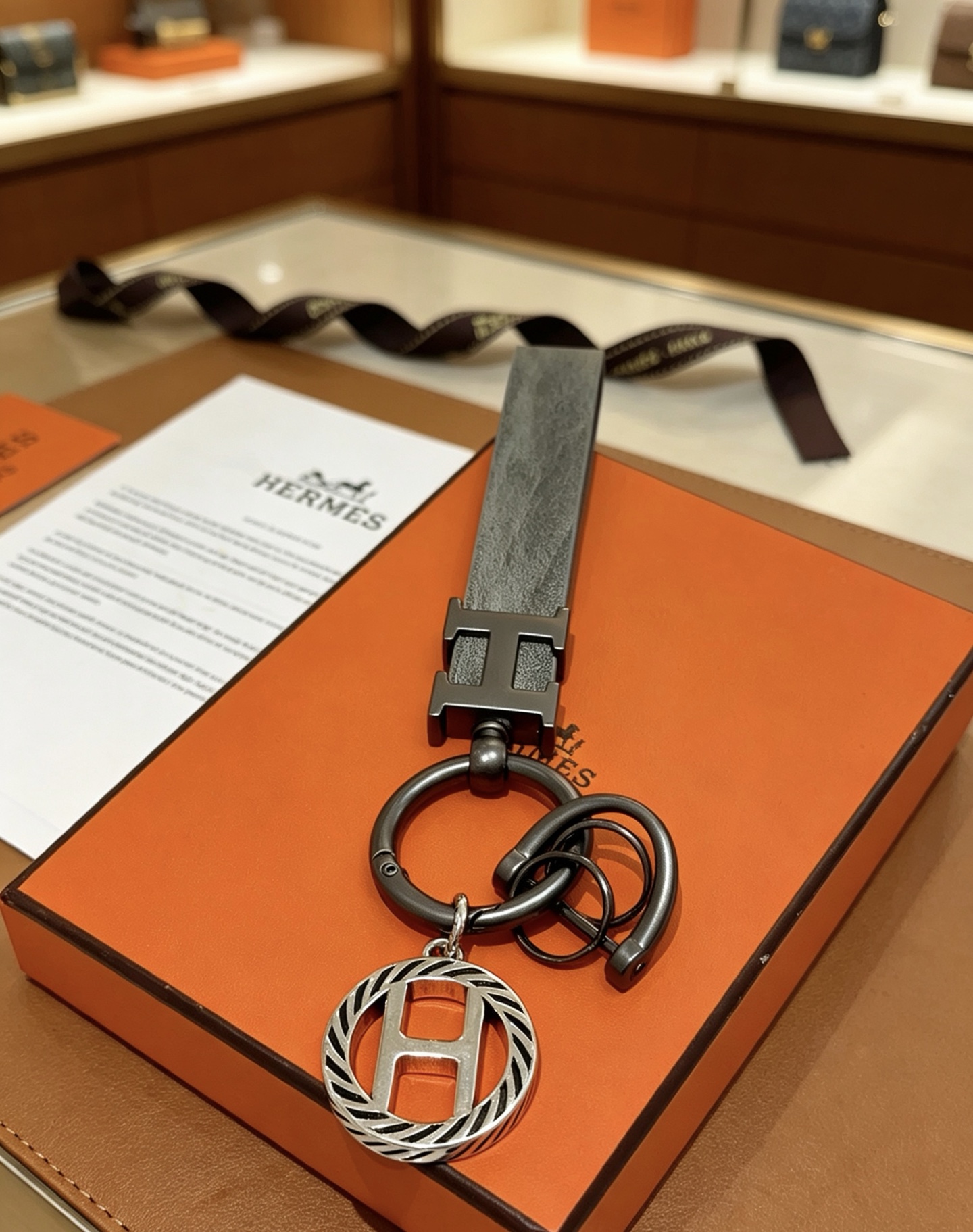 Hermes H Logo Leather Strap Keychain pendant Gunmetal gray metal matte gray leather strap silver-toned H charm with black striped detailing 10cm total length