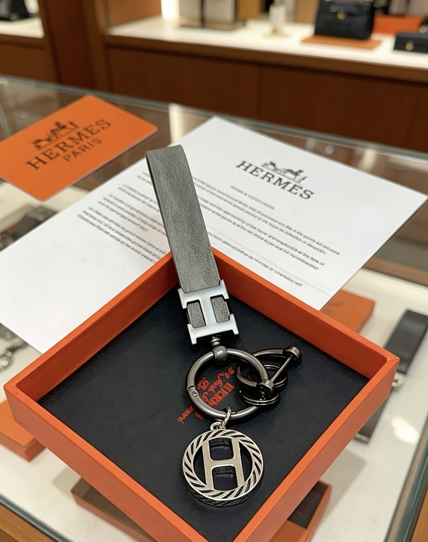 Hermes H Logo Leather Strap Keychain pendant Gunmetal gray metal matte gray leather strap silver-toned H charm with black striped detailing 10cm total length