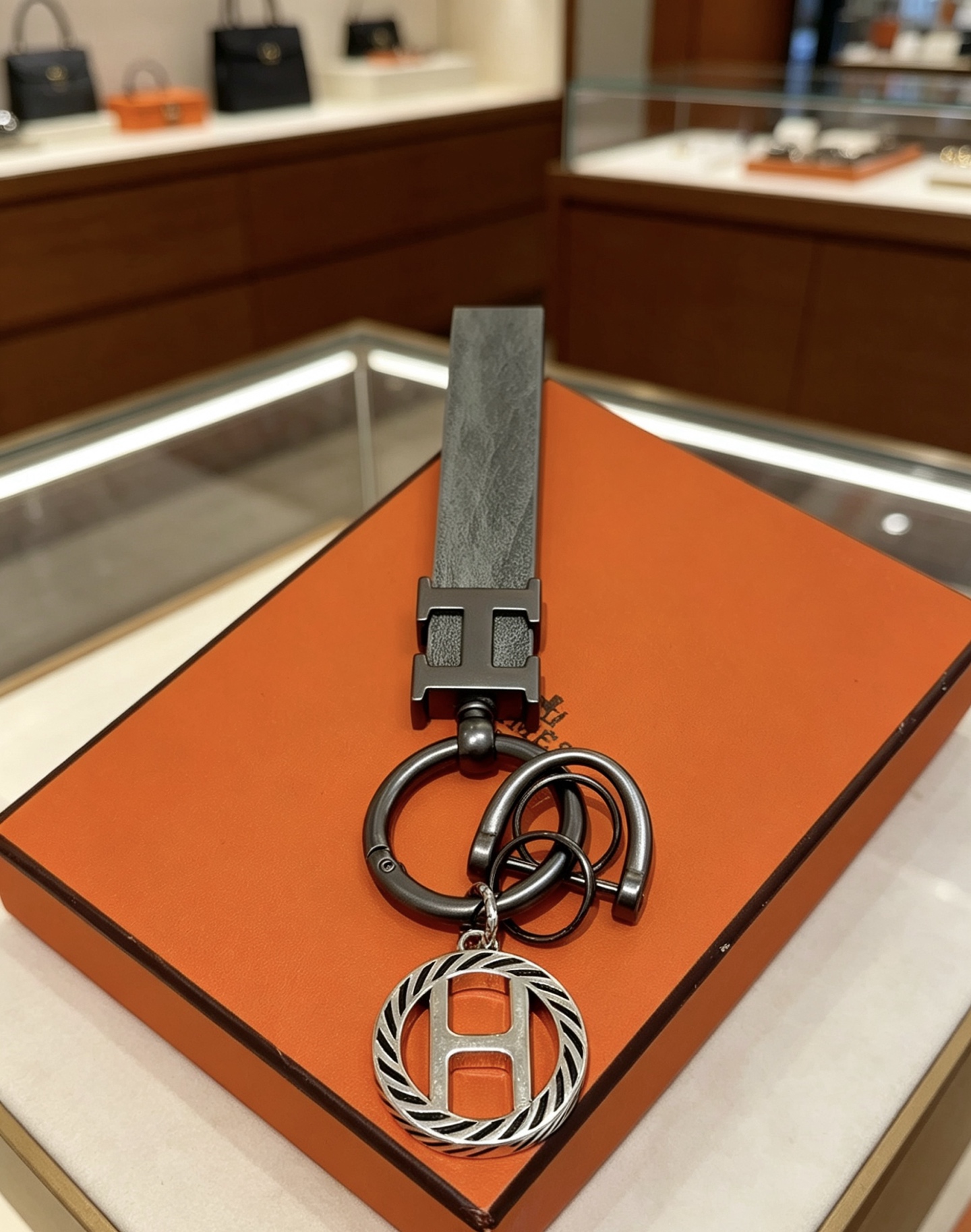 Hermes H Logo Leather Strap Keychain pendant Gunmetal gray metal matte gray leather strap silver-toned H charm with black striped detailing 10cm total length