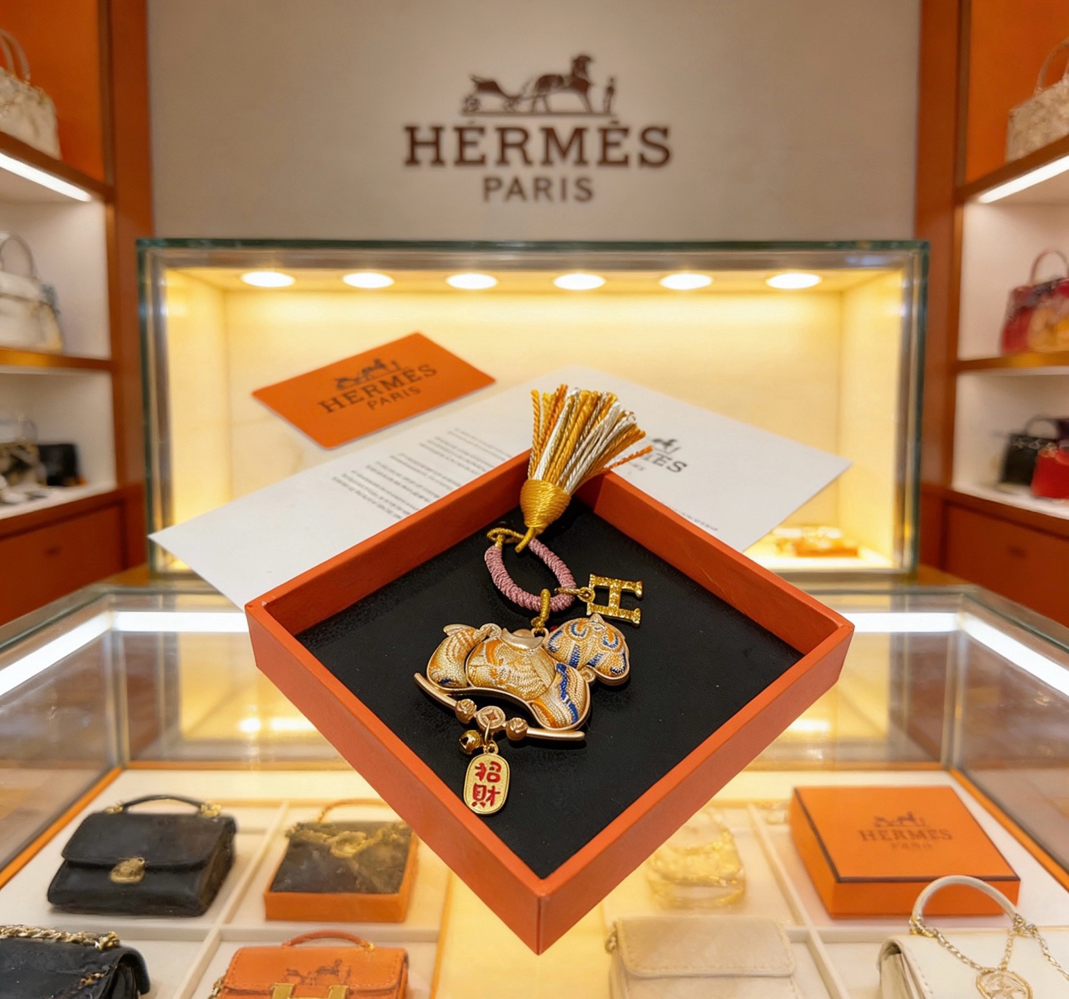 Pendentif porte-clés avec breloque cheval du Nouvel An chinois Hermes Métal doré Cordon tressé rose doré et pompon orange et blanc Tissu doré avec broderie bleue Breloque texte en émail rouge Longueur totale 12 cm